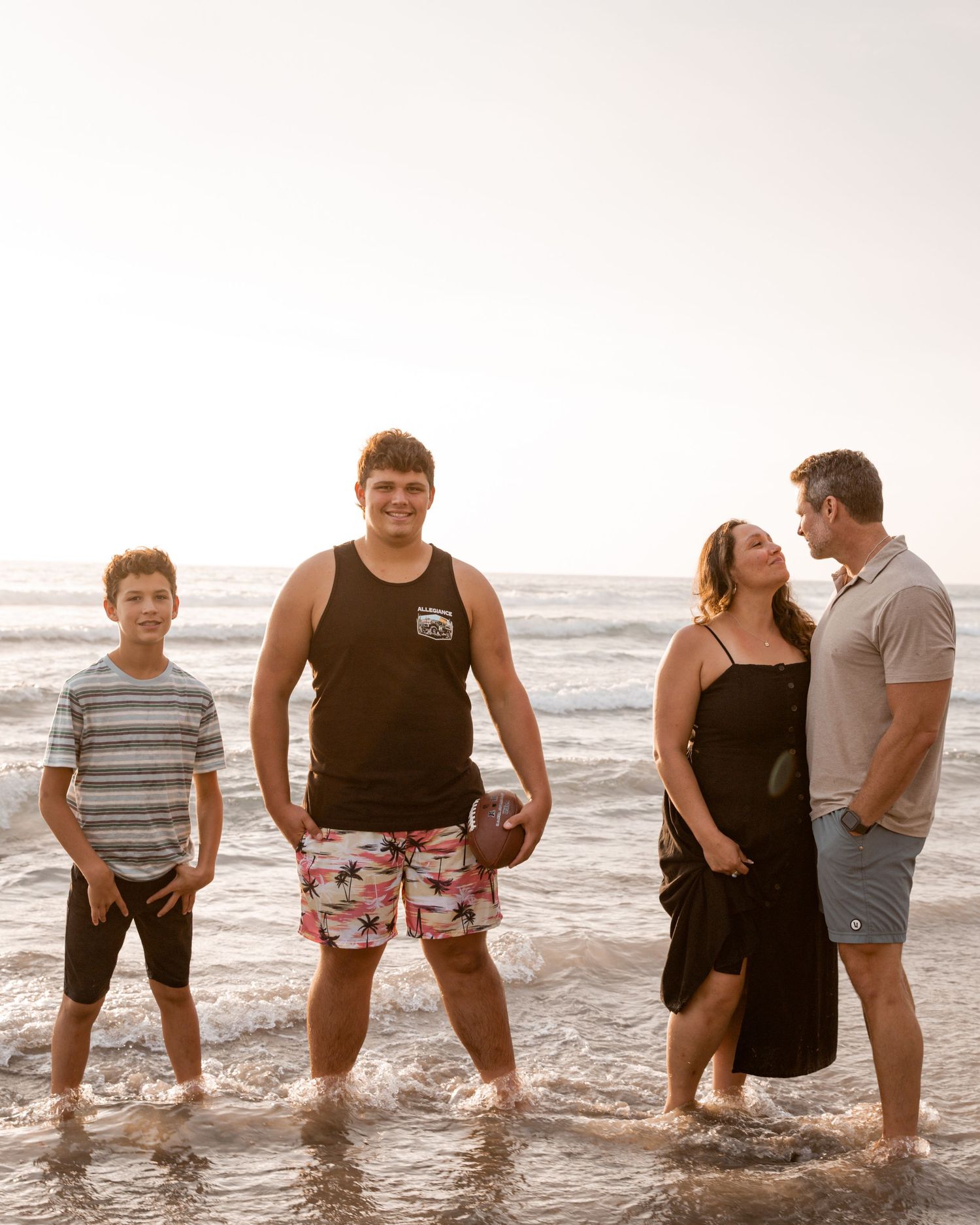 Group of friends having fun while standing in ocean waves at the beach.