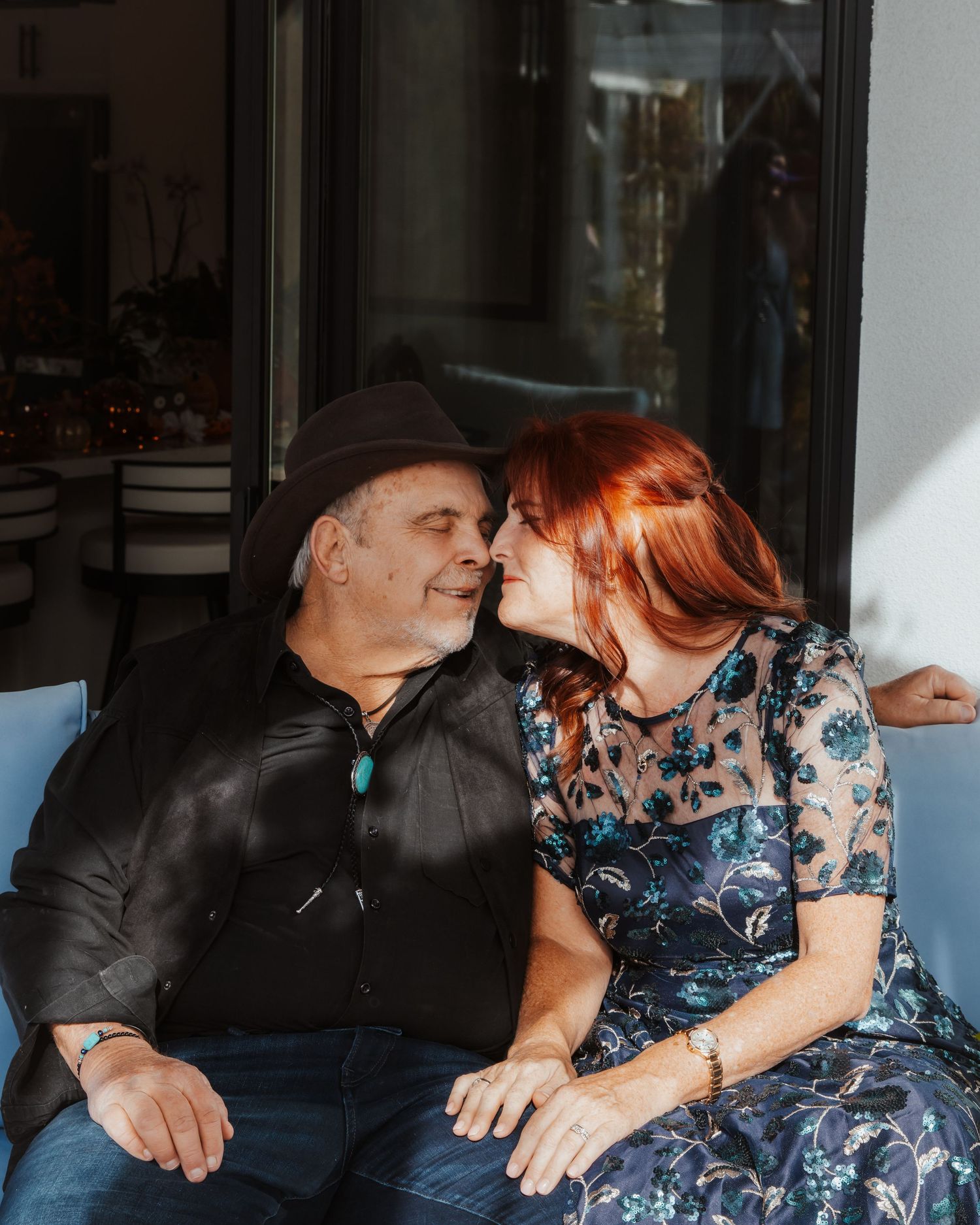 Couple sharing playful laughter while relaxing on indoor furniture.