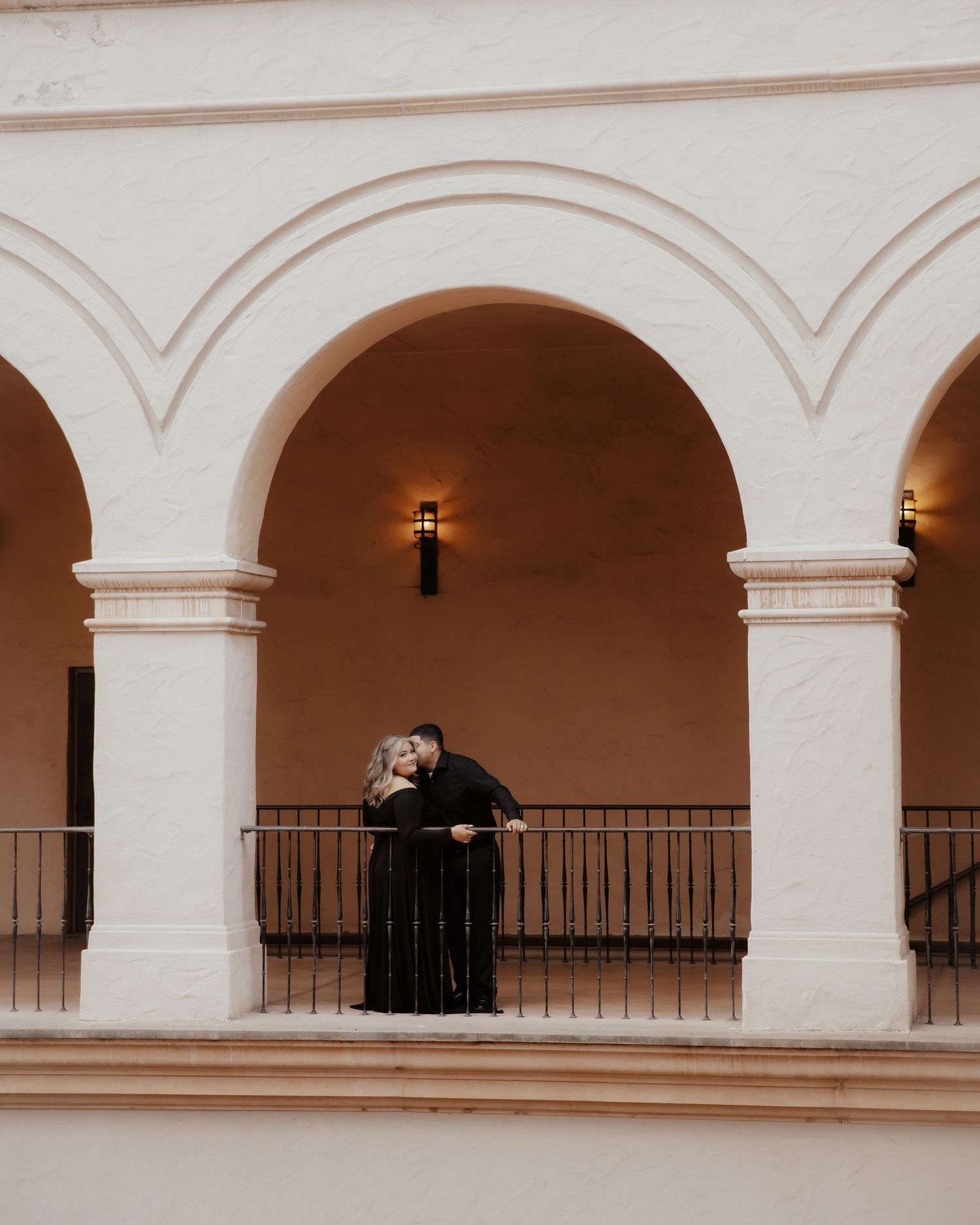 White arched colonnade with Spanish colonial architecture and distant figures.