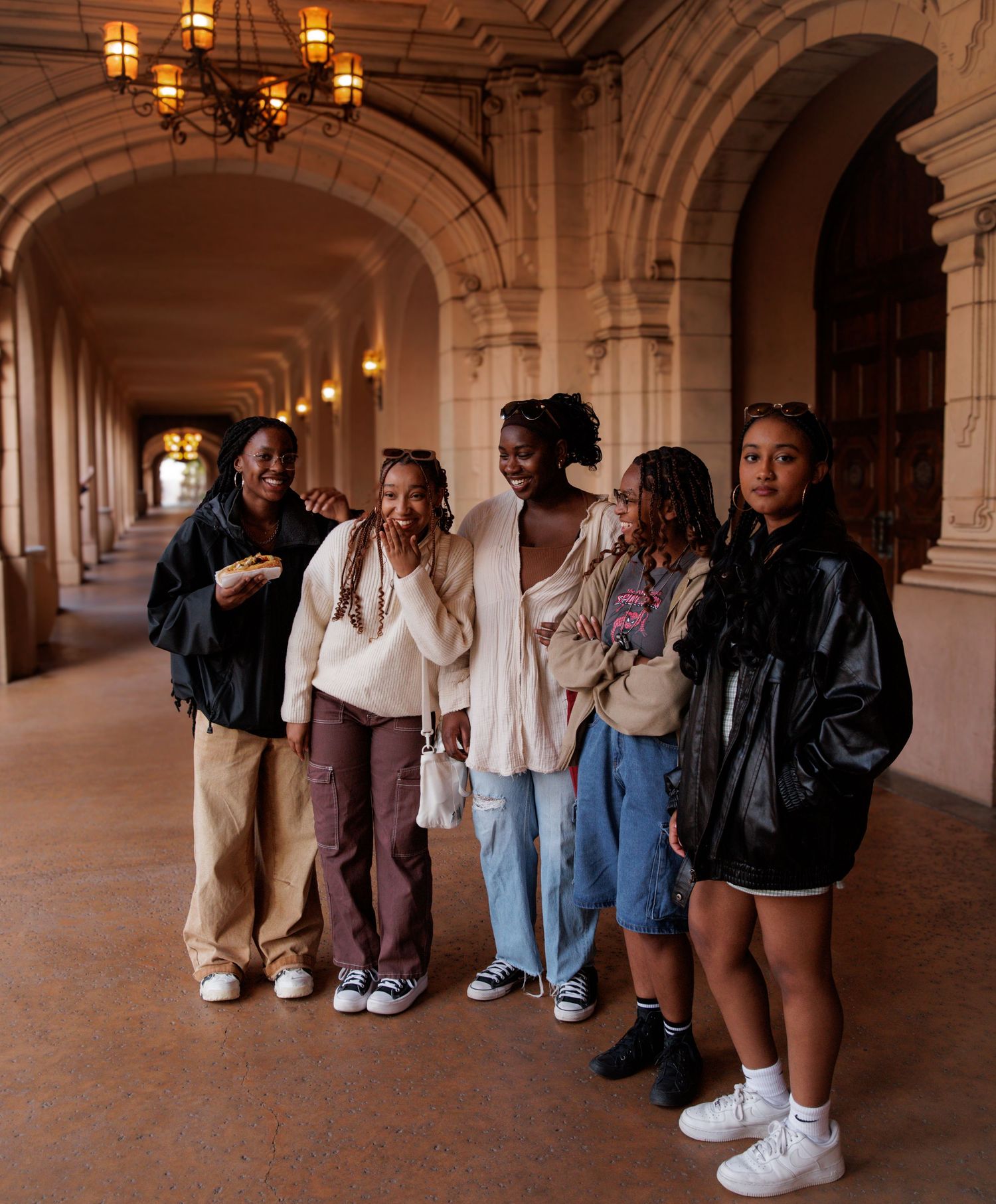 Friends posing casually in an ornate hallway with arched architecture.