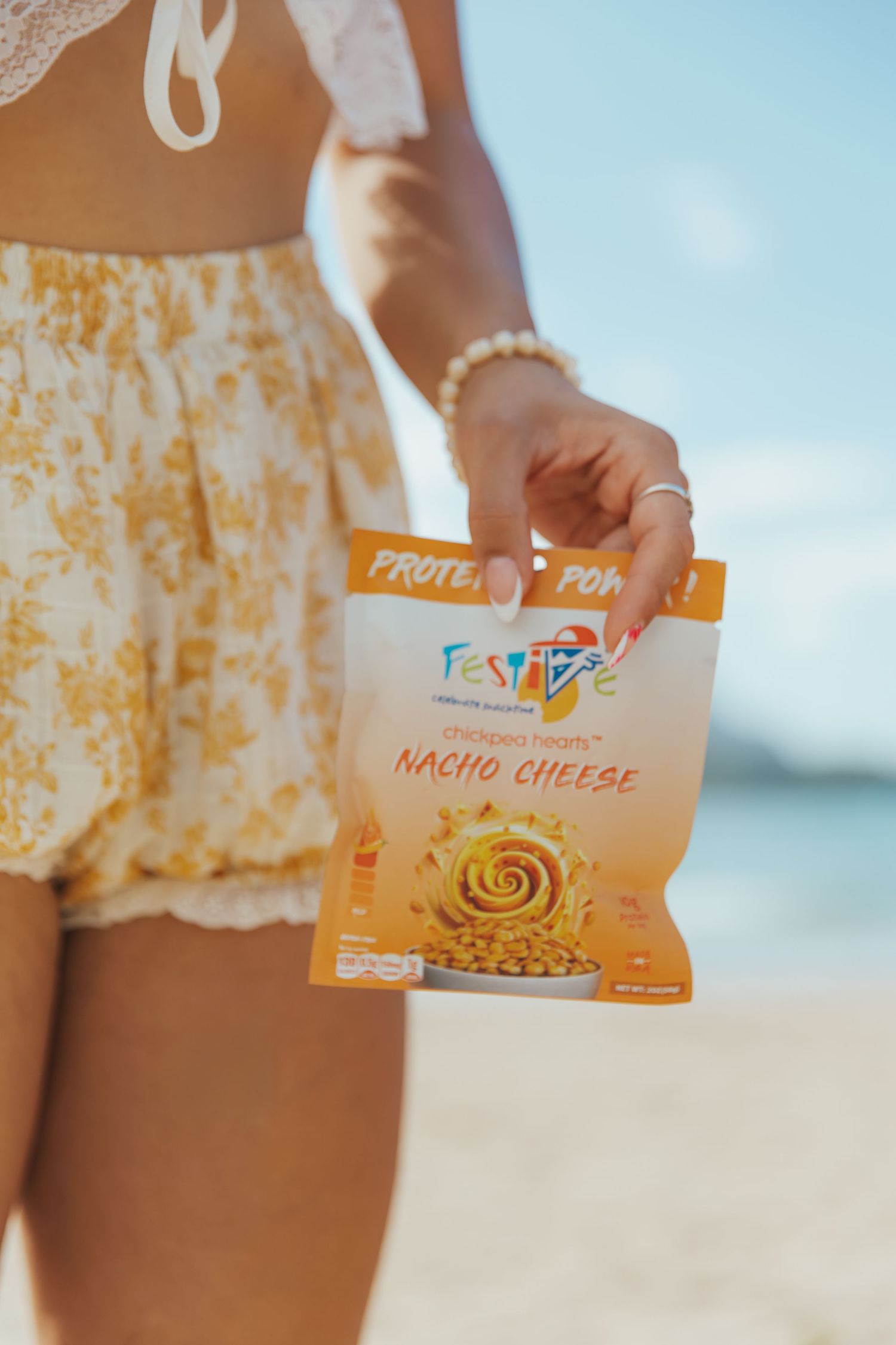 Hands holding colorful snack food packages against a white and orange patterned background.