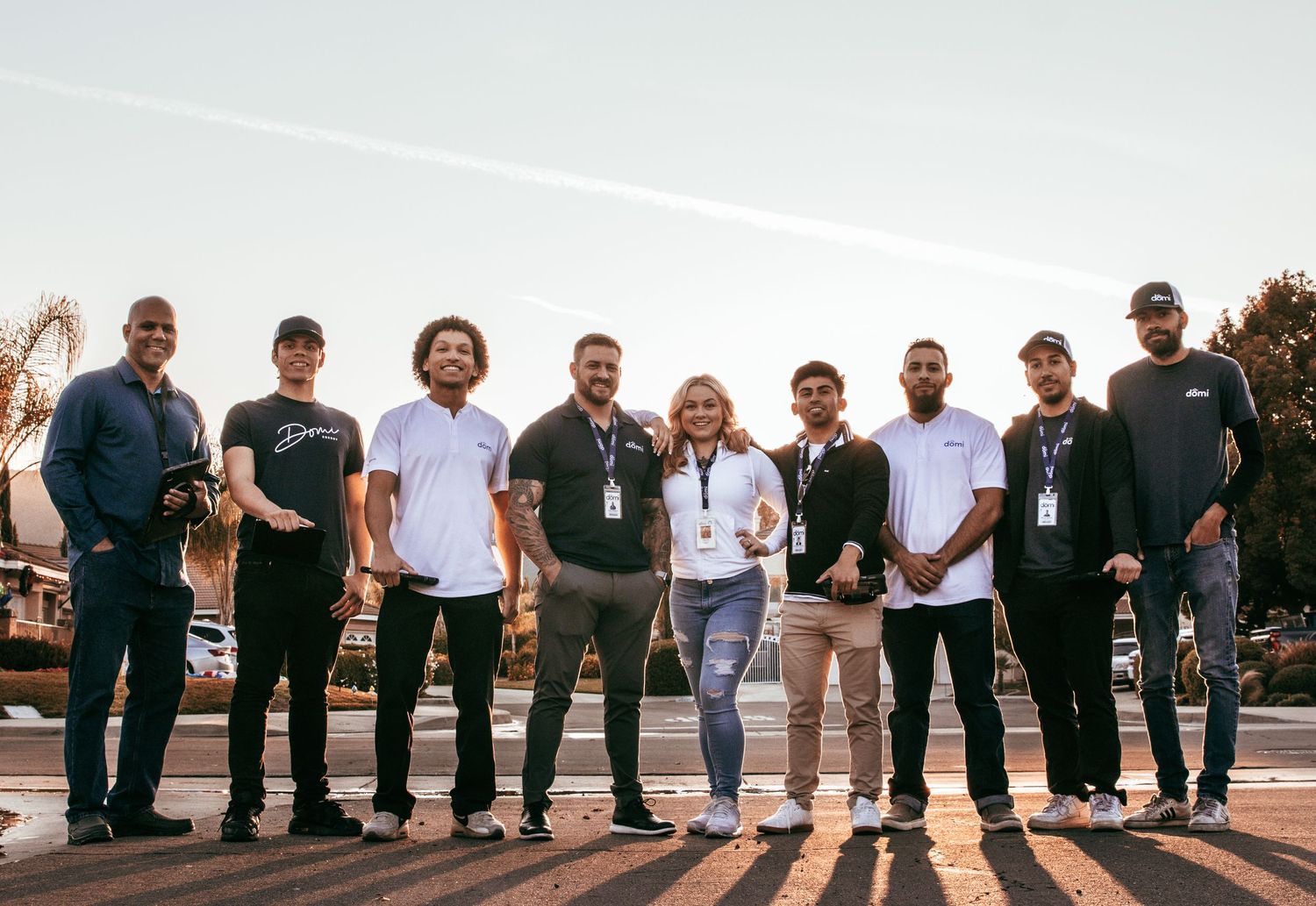 Group of professionals standing together outdoors in business attire against sunset backdrop.
