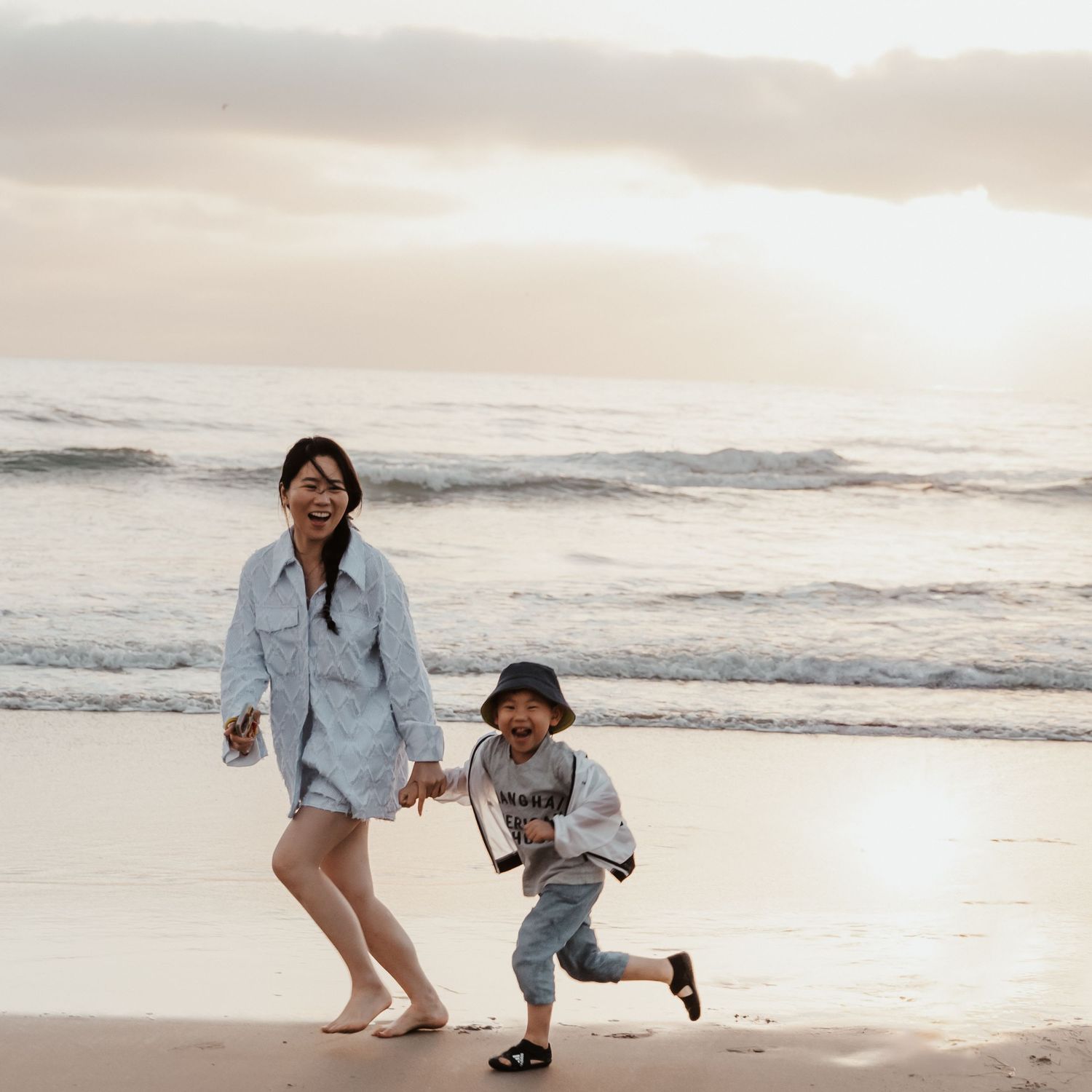 Two people playing and running together on a beach at sunset.