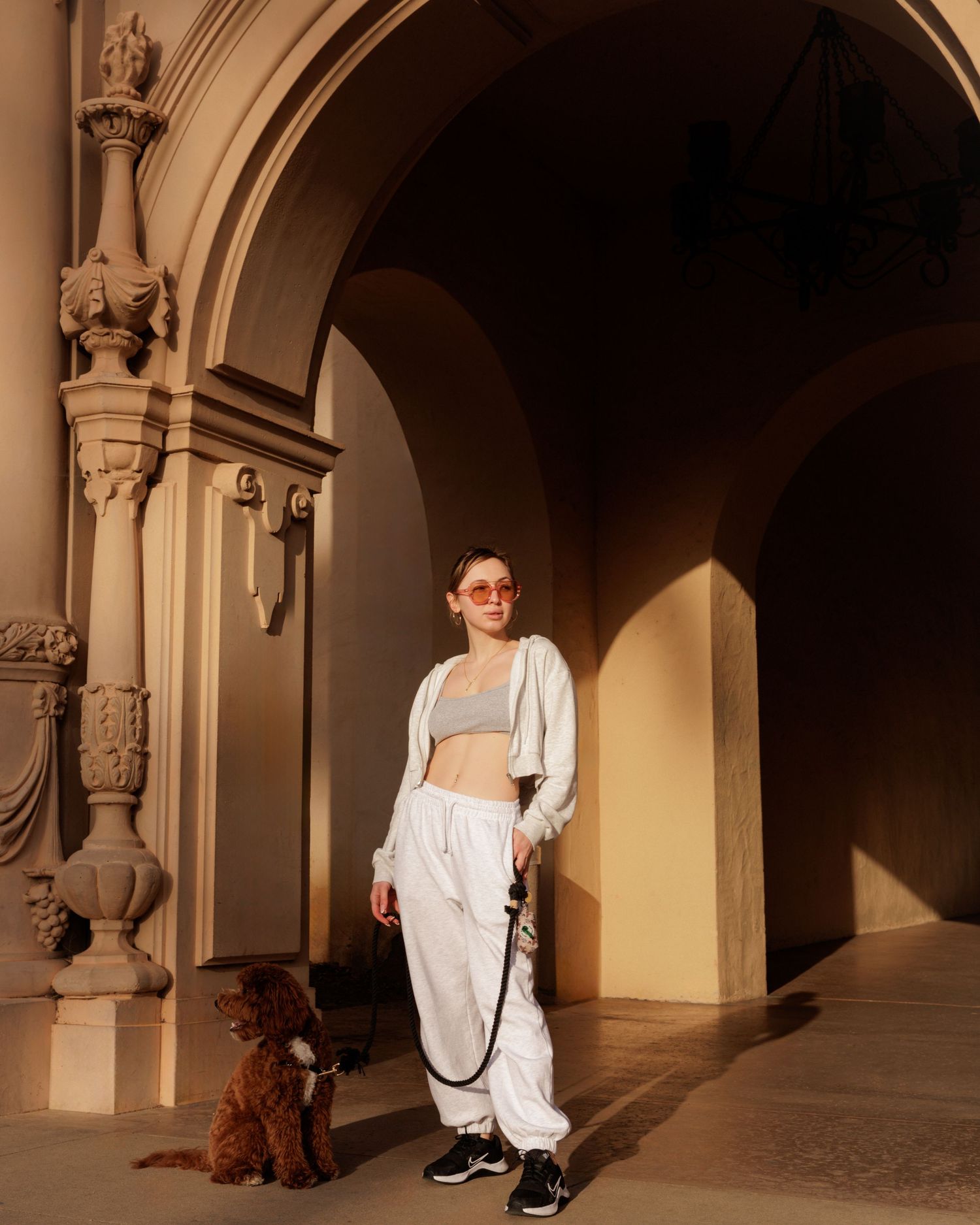 Person in white clothing walking through an elegant archway with stone columns.