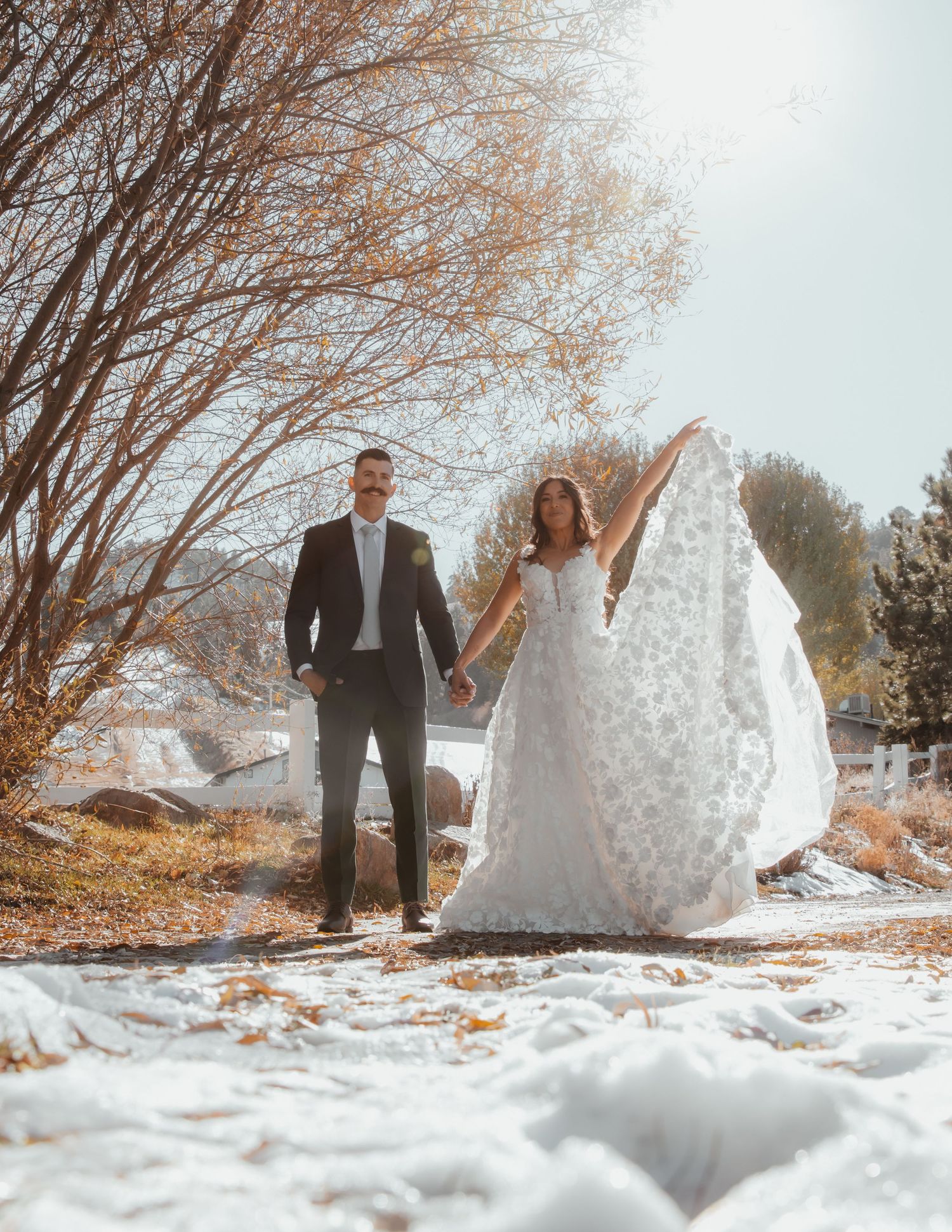 Winter wedding photos captured in snowy landscape with bare trees.