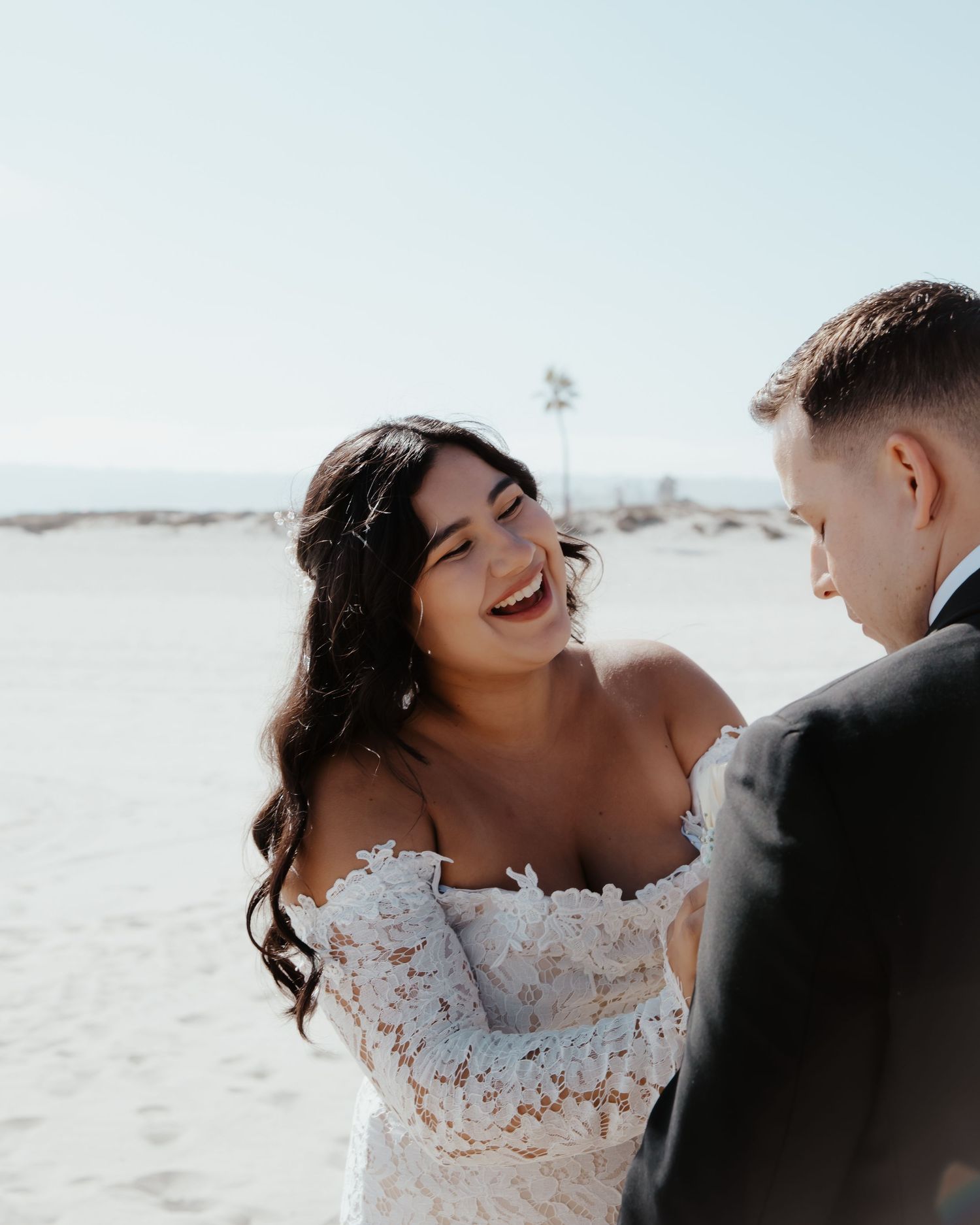 Happy couple shares joyful moment during their beach wedding photoshoot.
