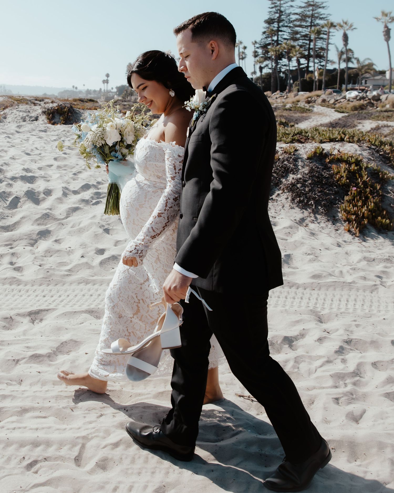 A couple playfully kicks sand during their beach wedding photoshoot.