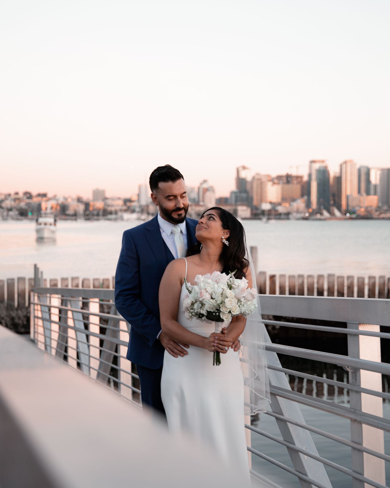 Romantic waterfront wedding photos with downtown San Diego skyline at sunset.