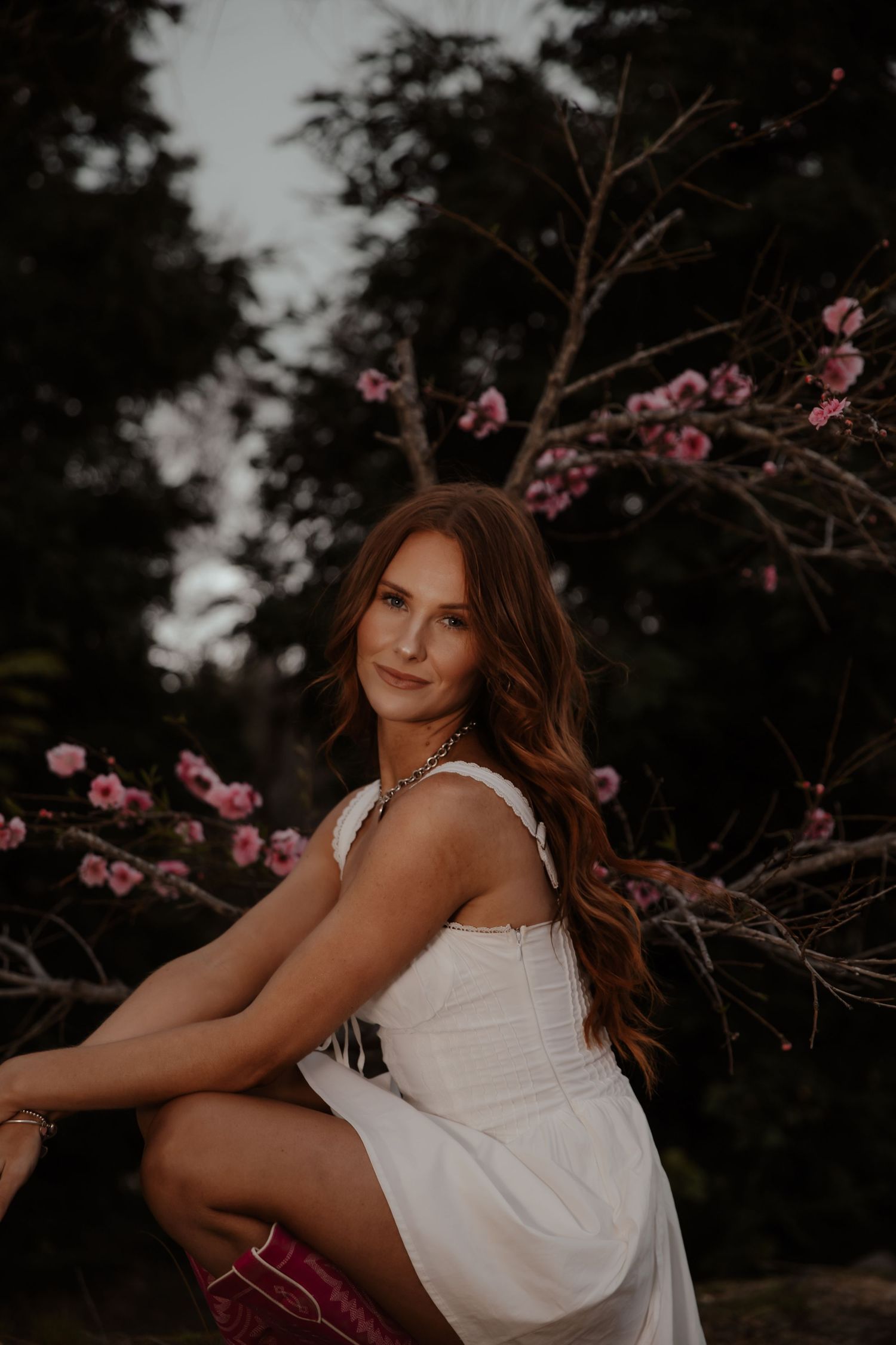 Romantic portrait session in a garden with cherry blossoms at dusk.