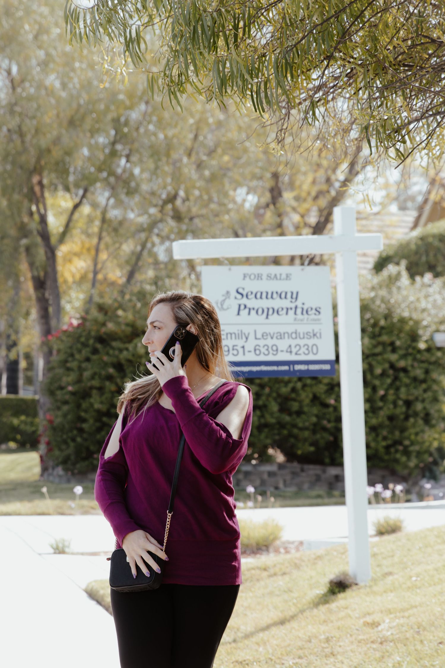Emotional embrace captured in front of real estate signs on suburban lawn.