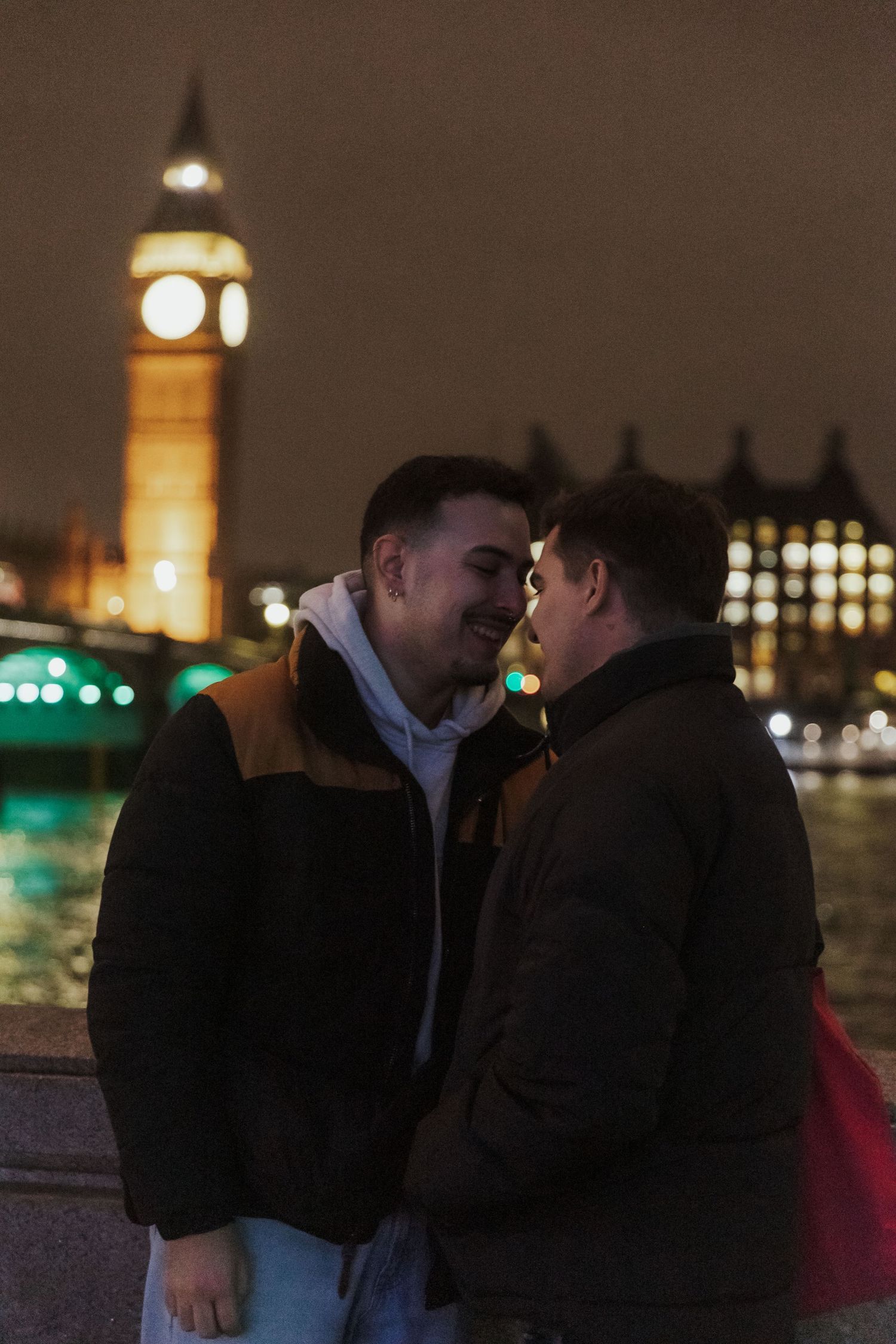 A romantic nighttime scene along the Thames with Big Ben illuminated in the background and city lights reflecting on the water.