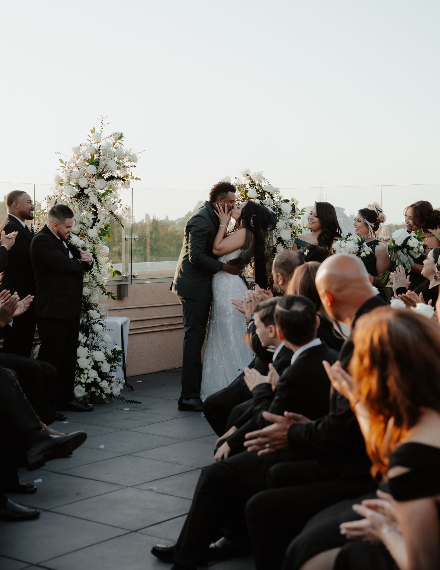Outdoor wedding ceremony with guests seated and floral arrangements decorating the venue.