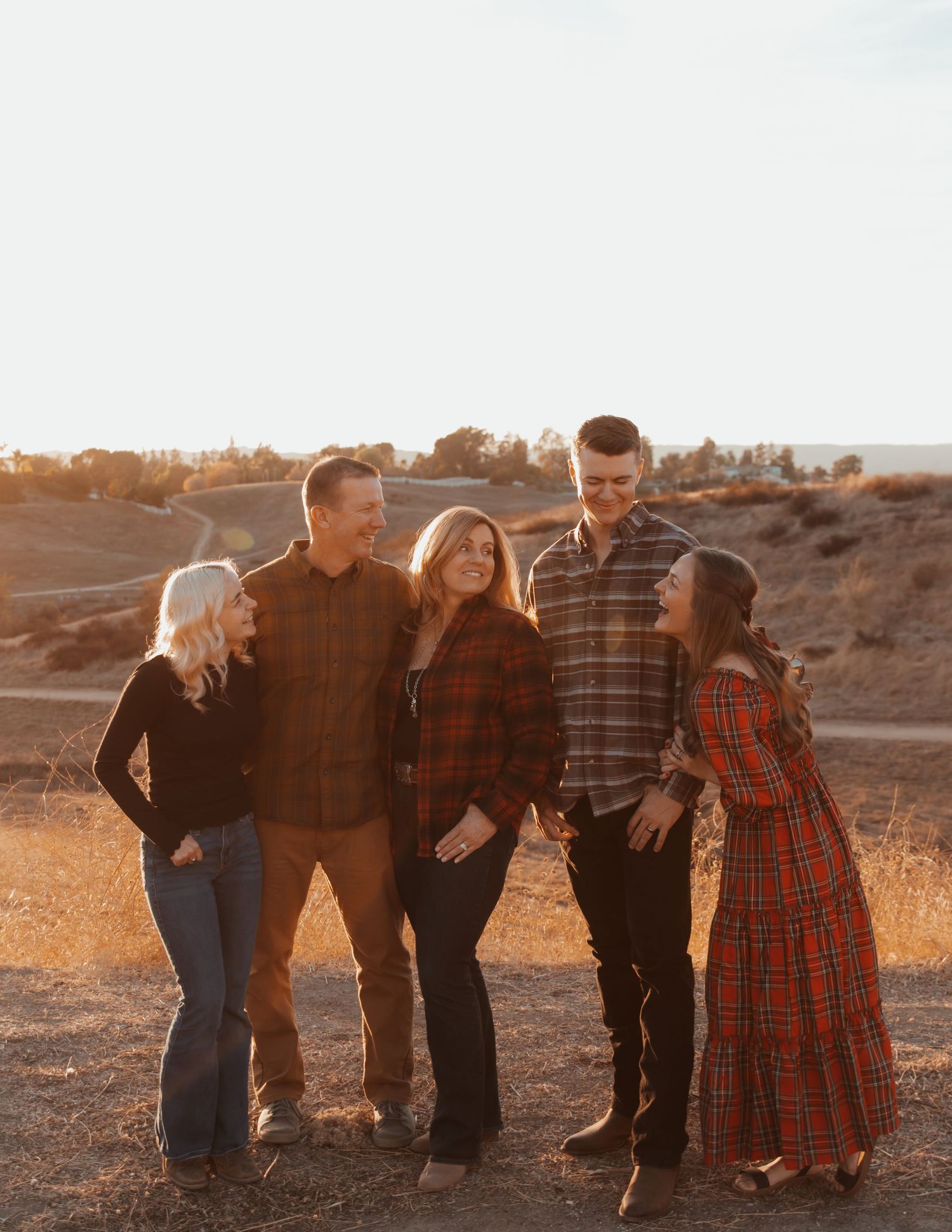 Family group posing together at sunset in coordinated outfits on desert terrain.