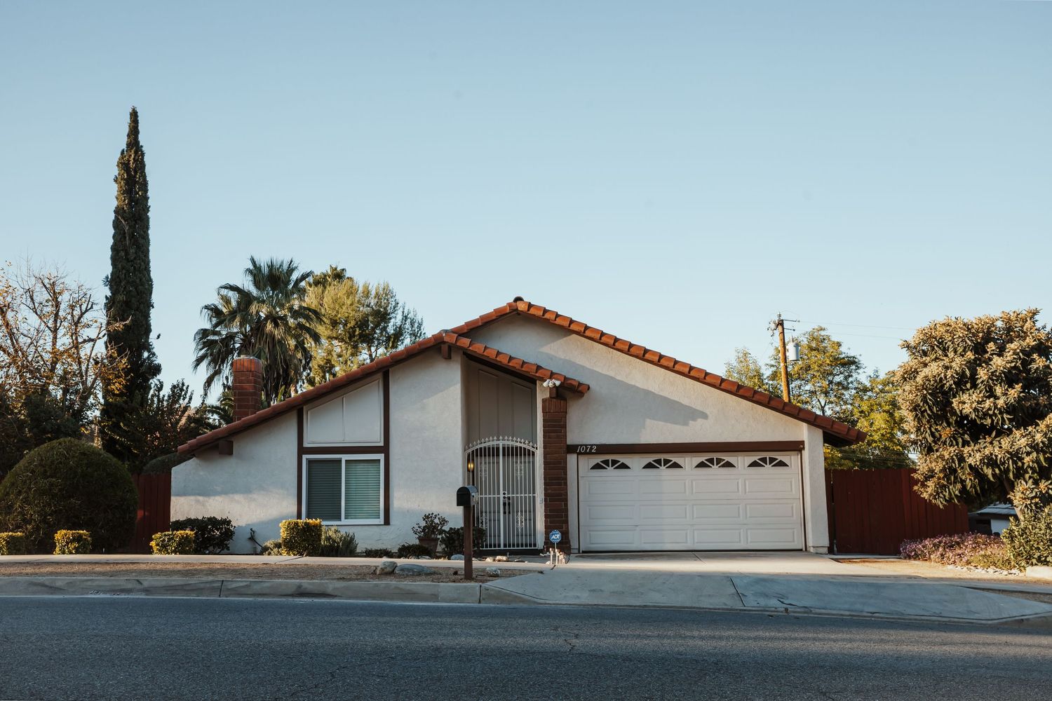 Row of suburban single-story homes with Spanish tile roofs under blue sky.