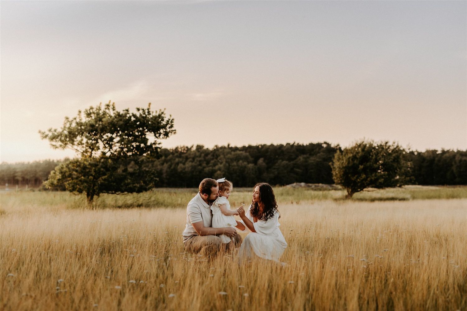 Familjefotografering på en äng under golden hour.