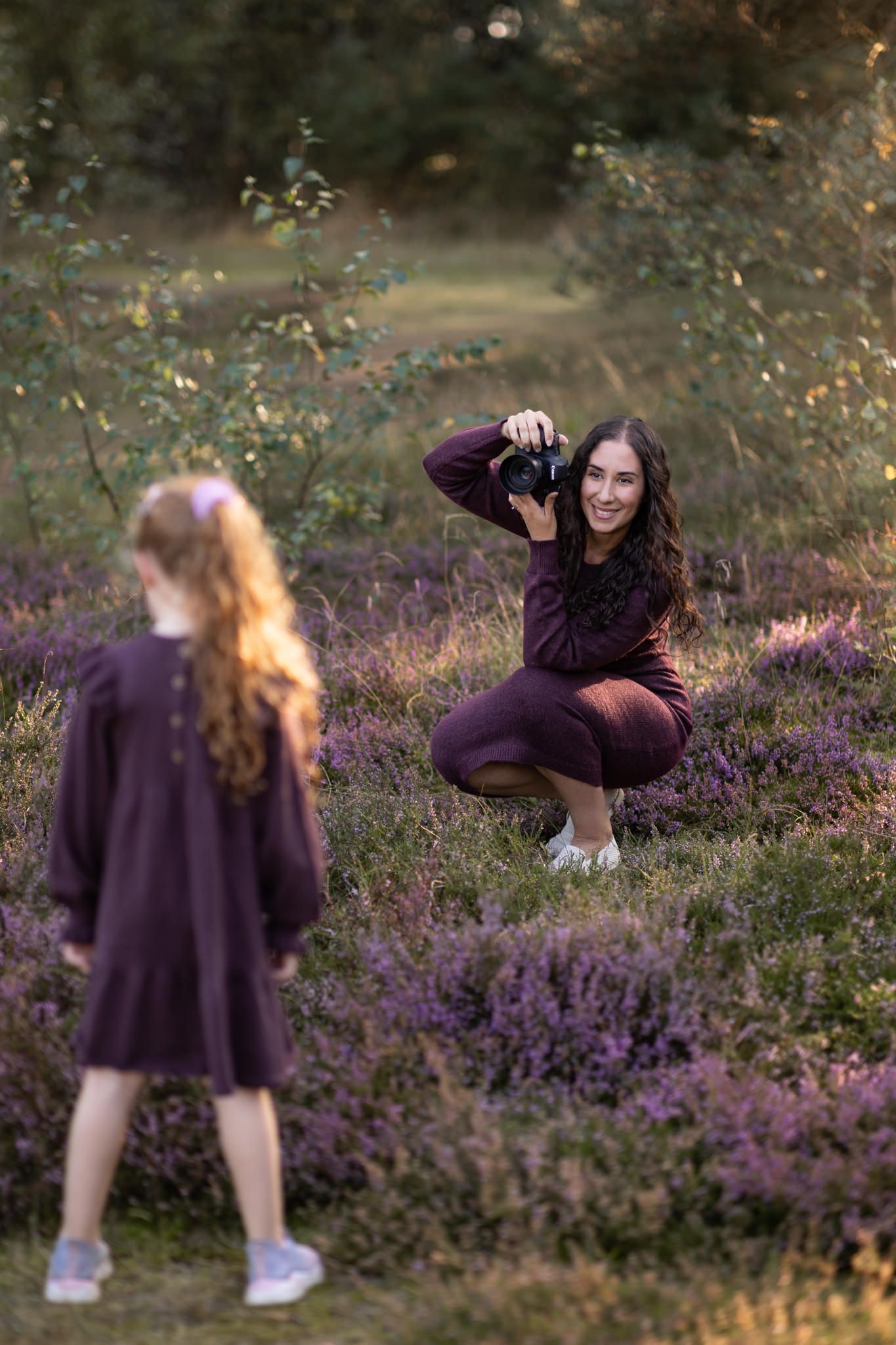 Fotograf Amira Rosell som sitter på huk under en barnfotografering ute i naturen och ska ta en bild på en 5-årig flicka.