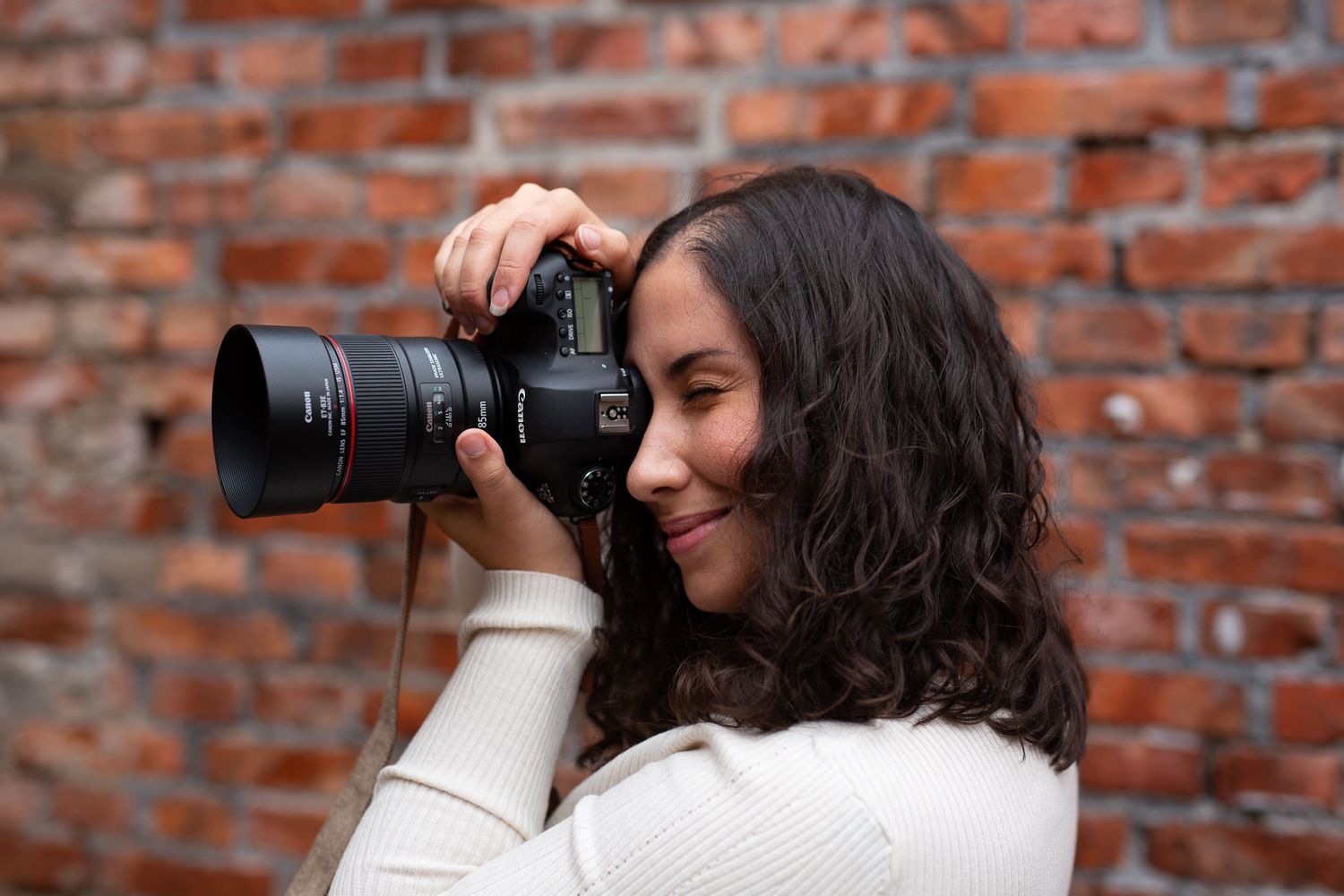 Bröllopsfotograf Amira Rosell in action. Hon står med en kamera i händerna och tittar in i sökaren för att ta en bild.