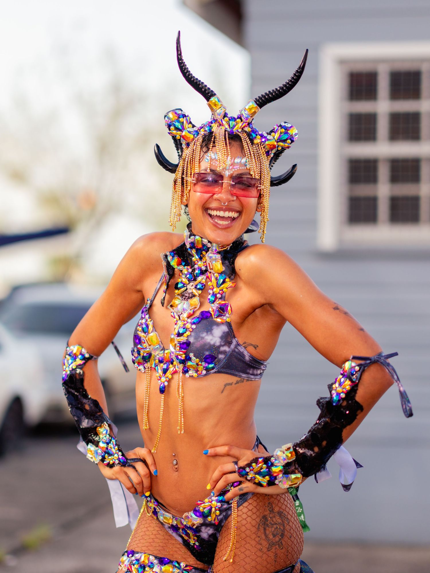 “Smiling carnival masquerader in a colorful beaded costume with horned headpiece posing during a Caribbean street parade.”