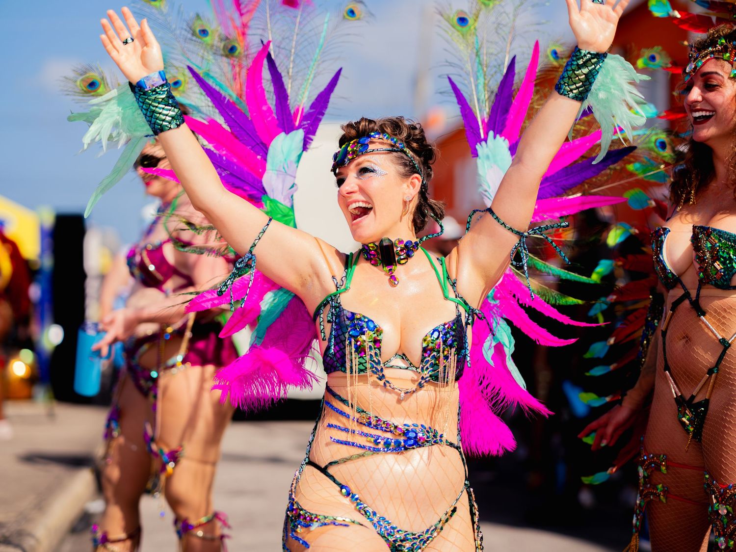 “Carnival dancer in vibrant feathered costume celebrating in the street during a colorful Caribbean parade.”