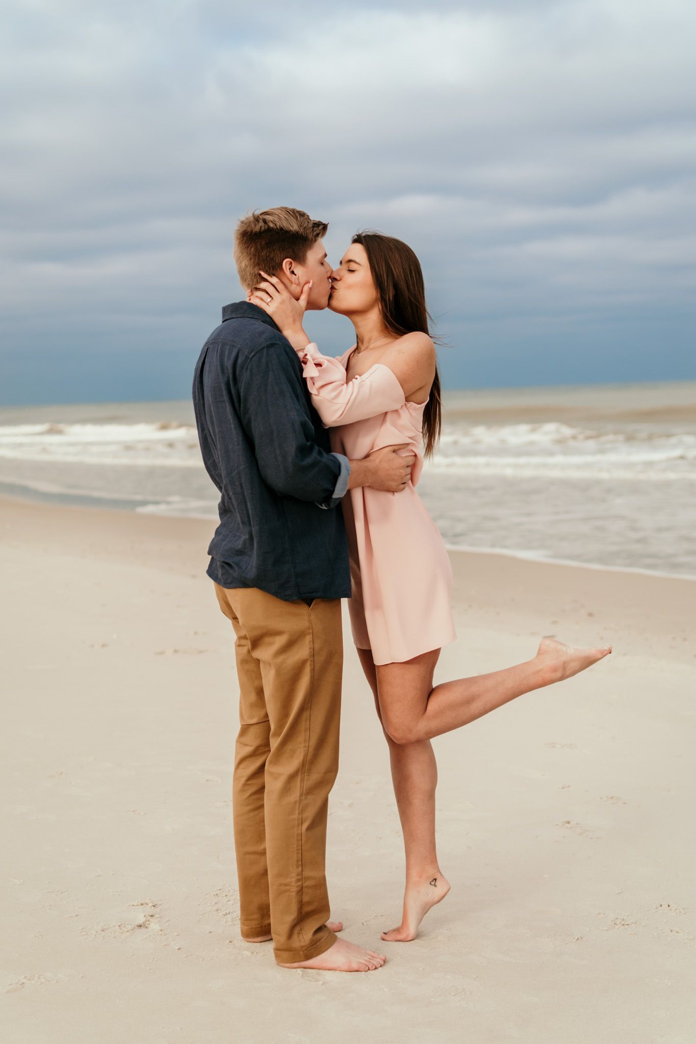 Couple walking and embracing together on the beach during a sunset engagement session