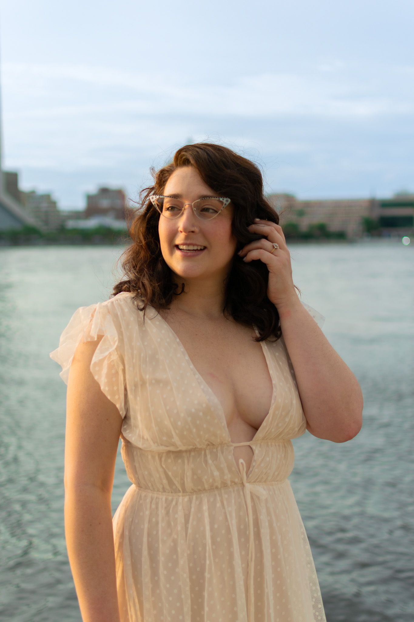 Woman standing by the water during a beach engagement portrait session at sunset
