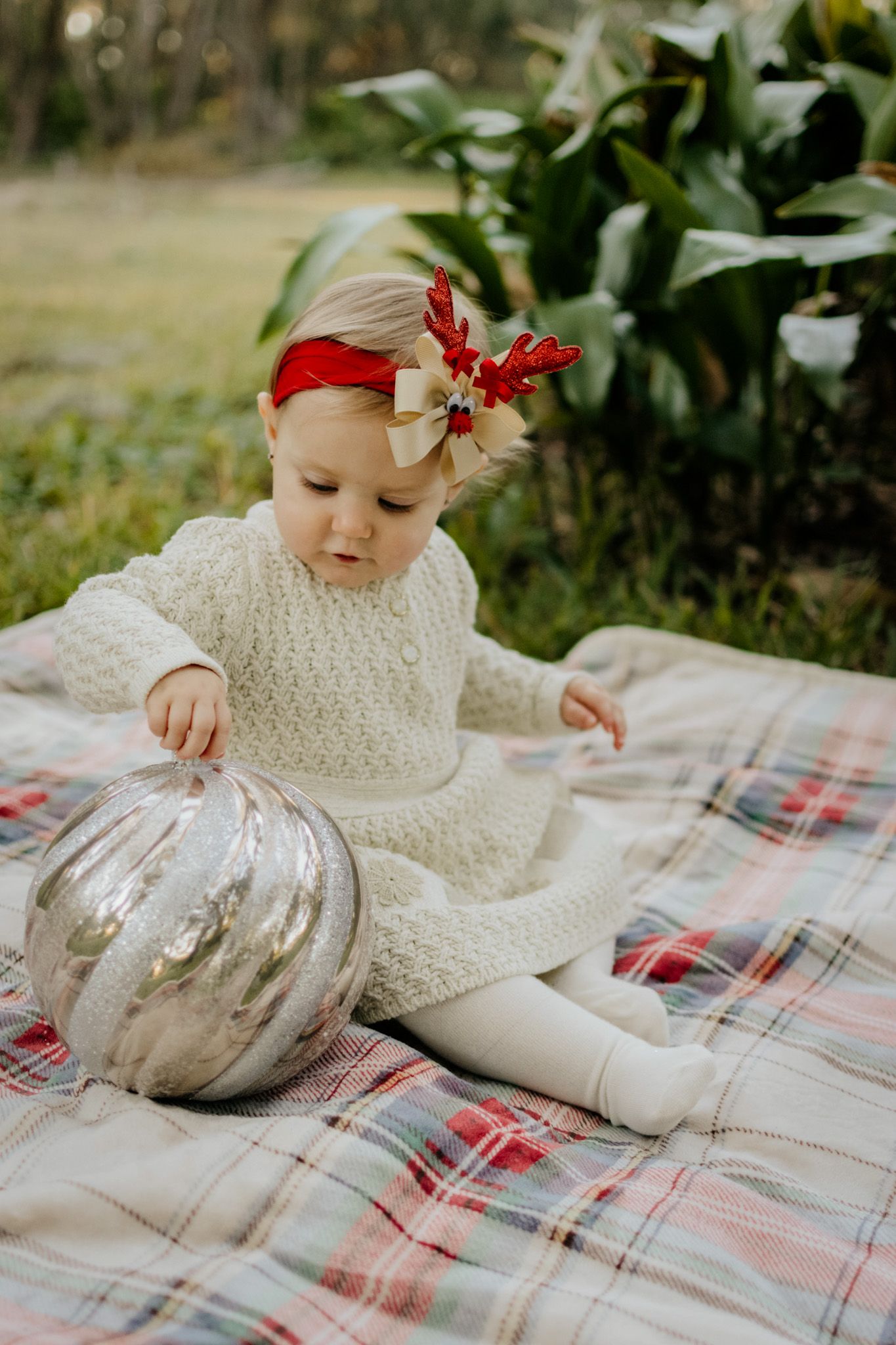 Baby lying on a blanket outdoors during a soft natural light lifestyle newborn session
