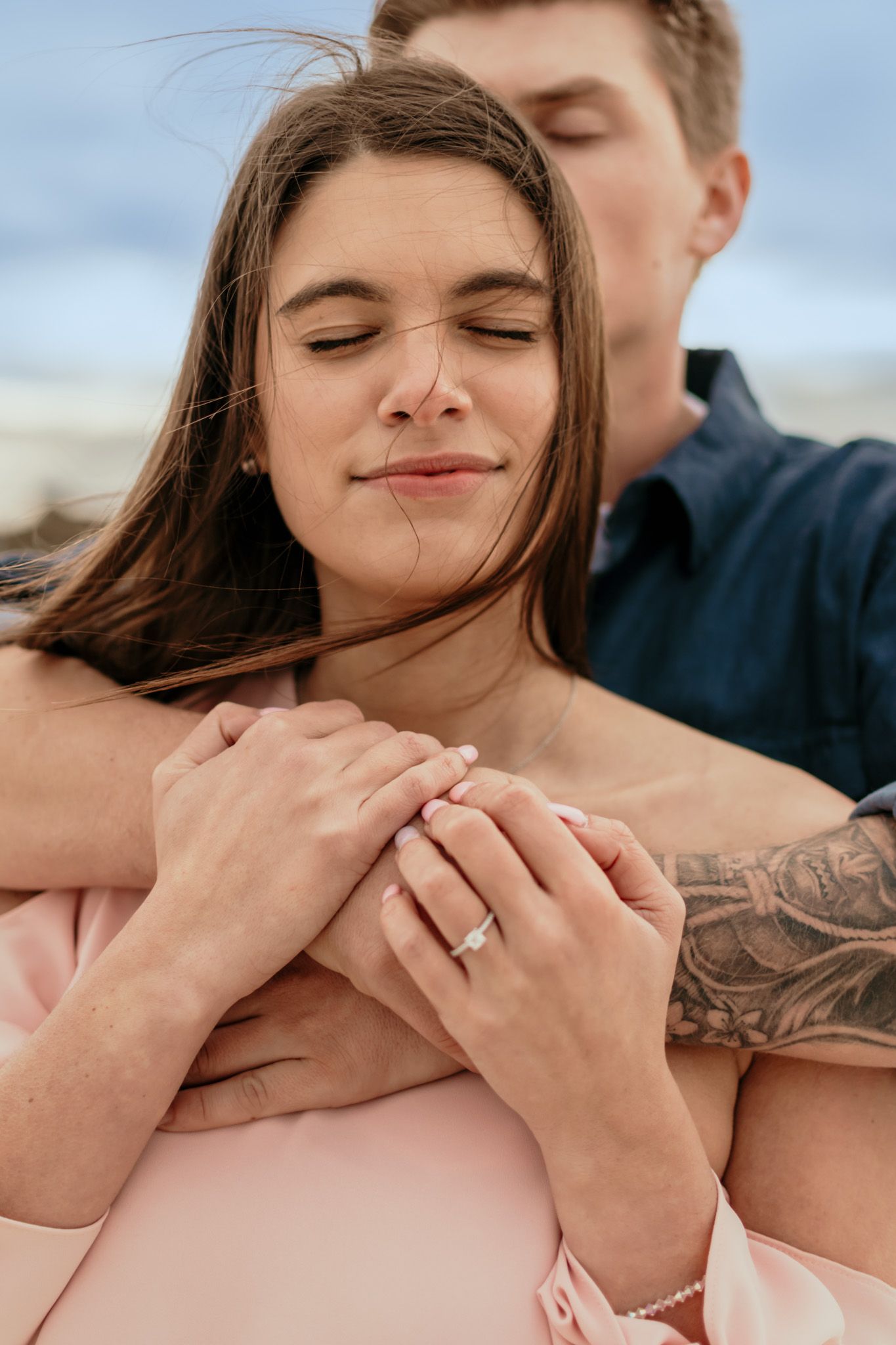 Couple embracing together on the beach during a sunset engagement session