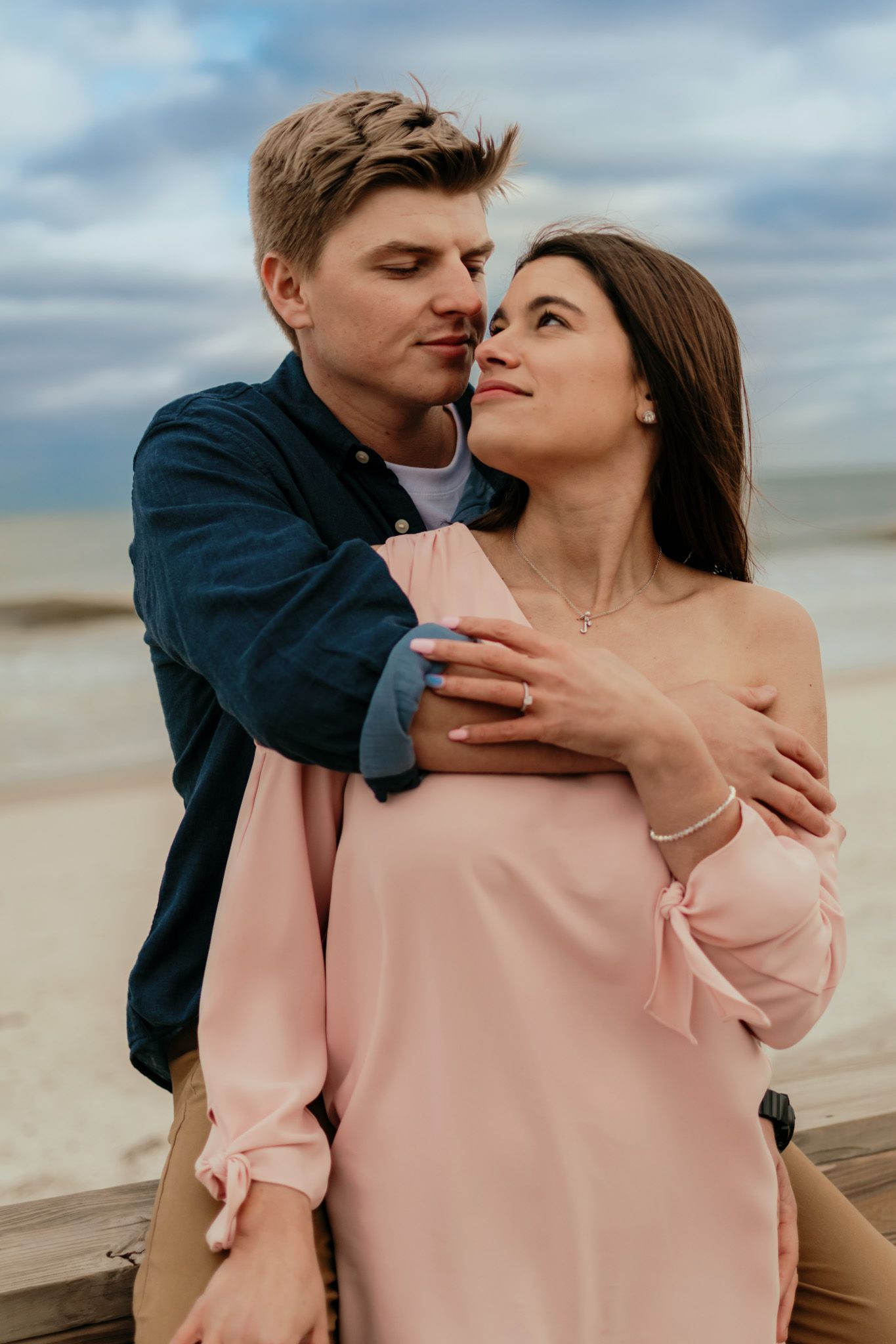 Couple embracing together on the beach during a sunset engagement session