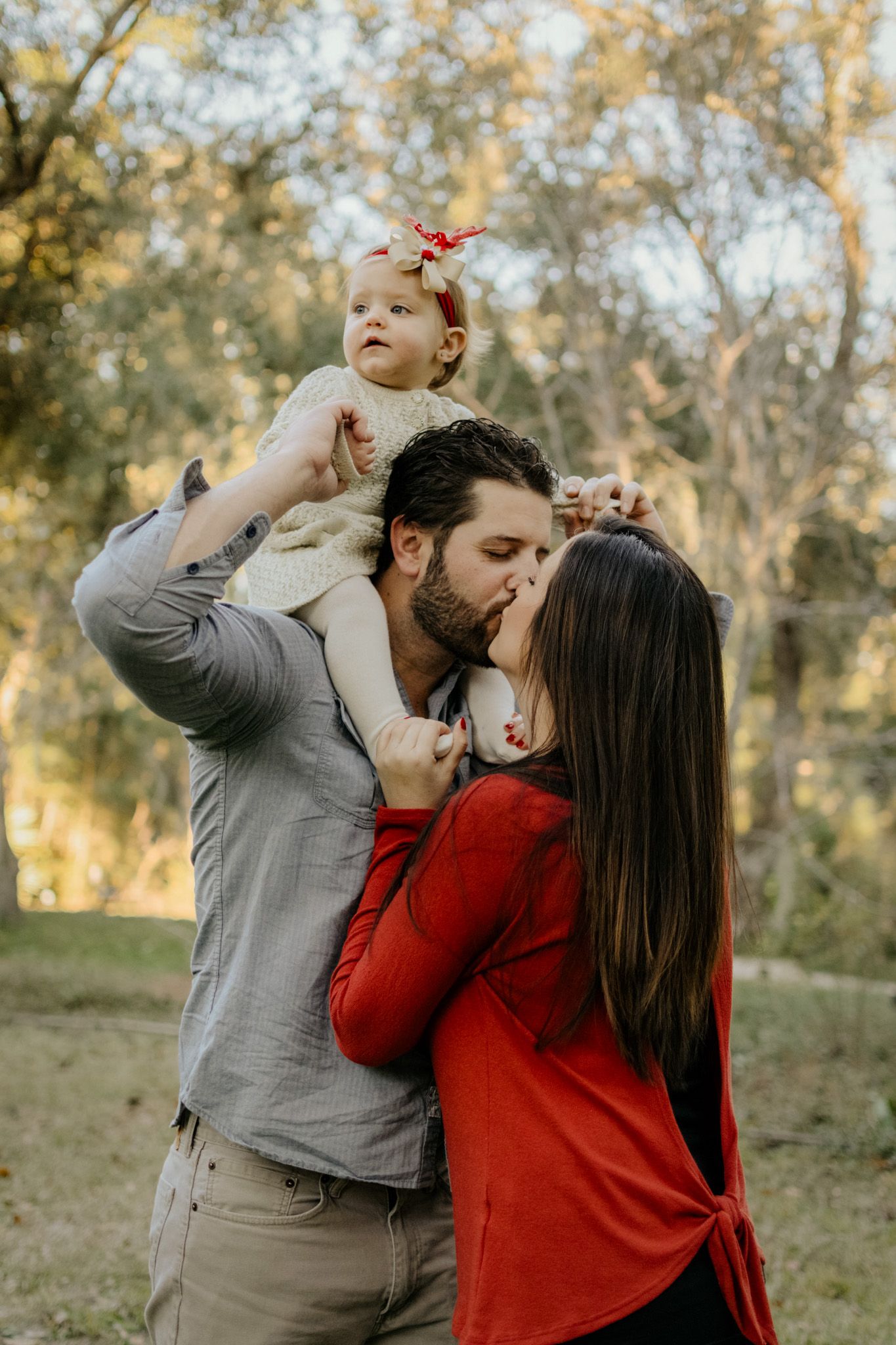 Couple and baby embracing outdoors during a family lifestyle engagement session with warm natural light