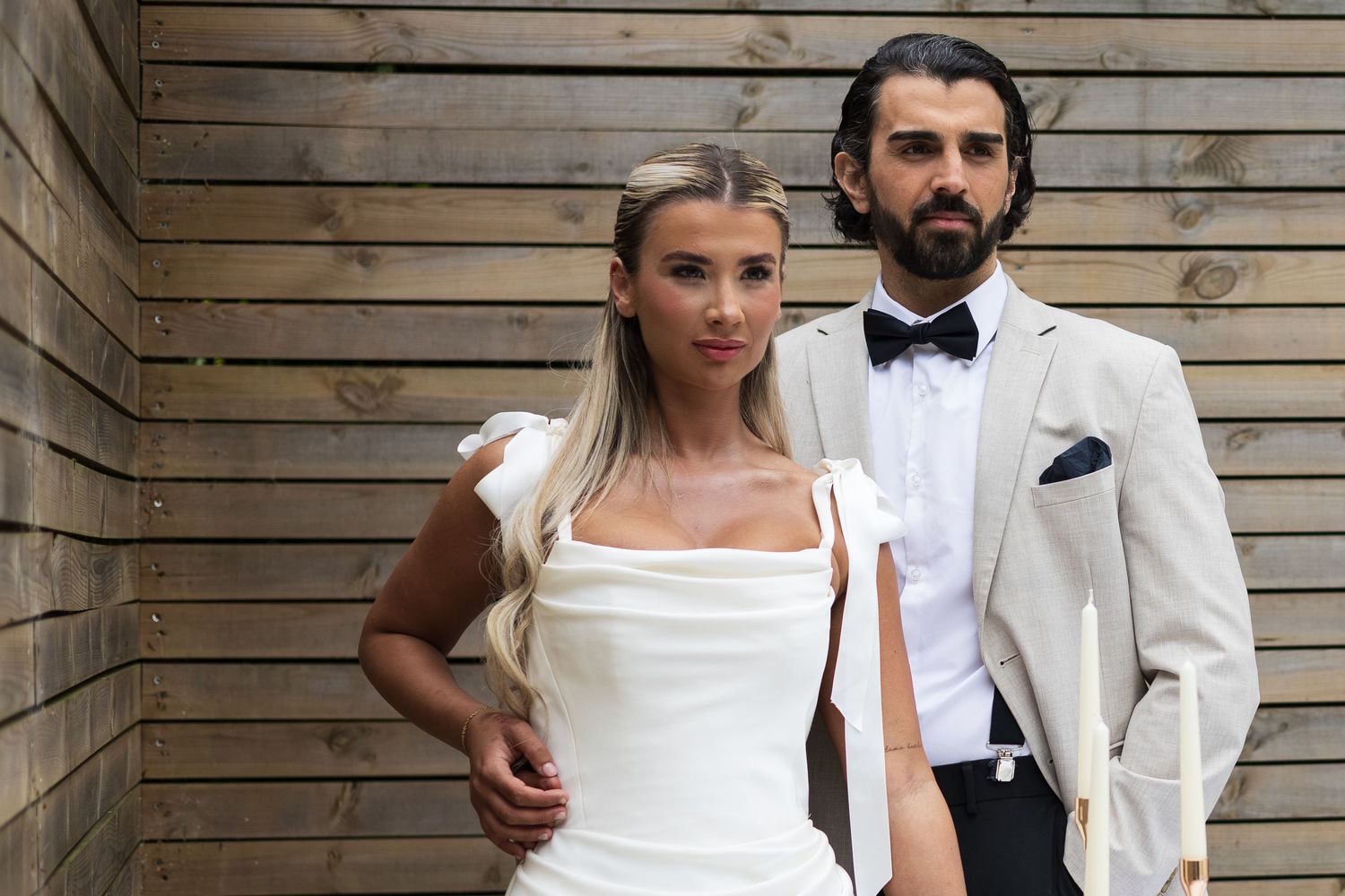 Bride and groom posing together against a wooden backdrop, de courceys manor