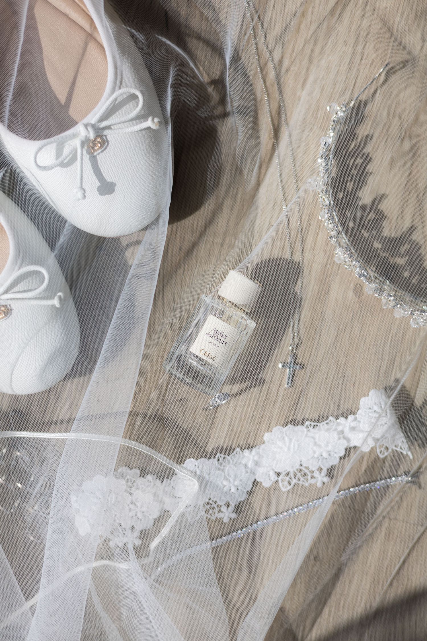 Bride's wedding shoes and accessories laid out on a wooden surface