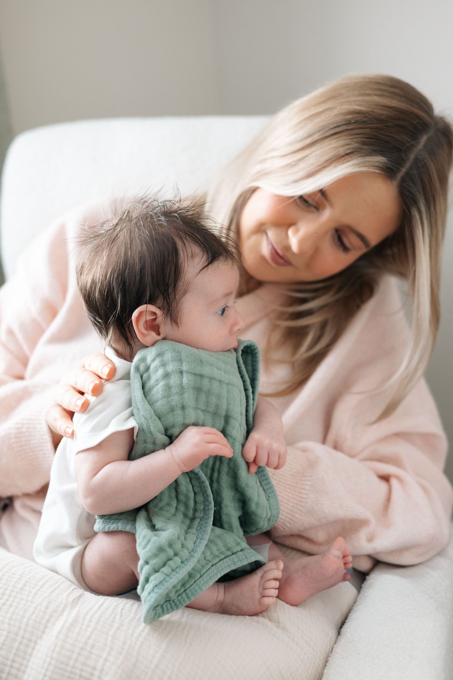 Mother cuddling her newborn baby gently on a bed