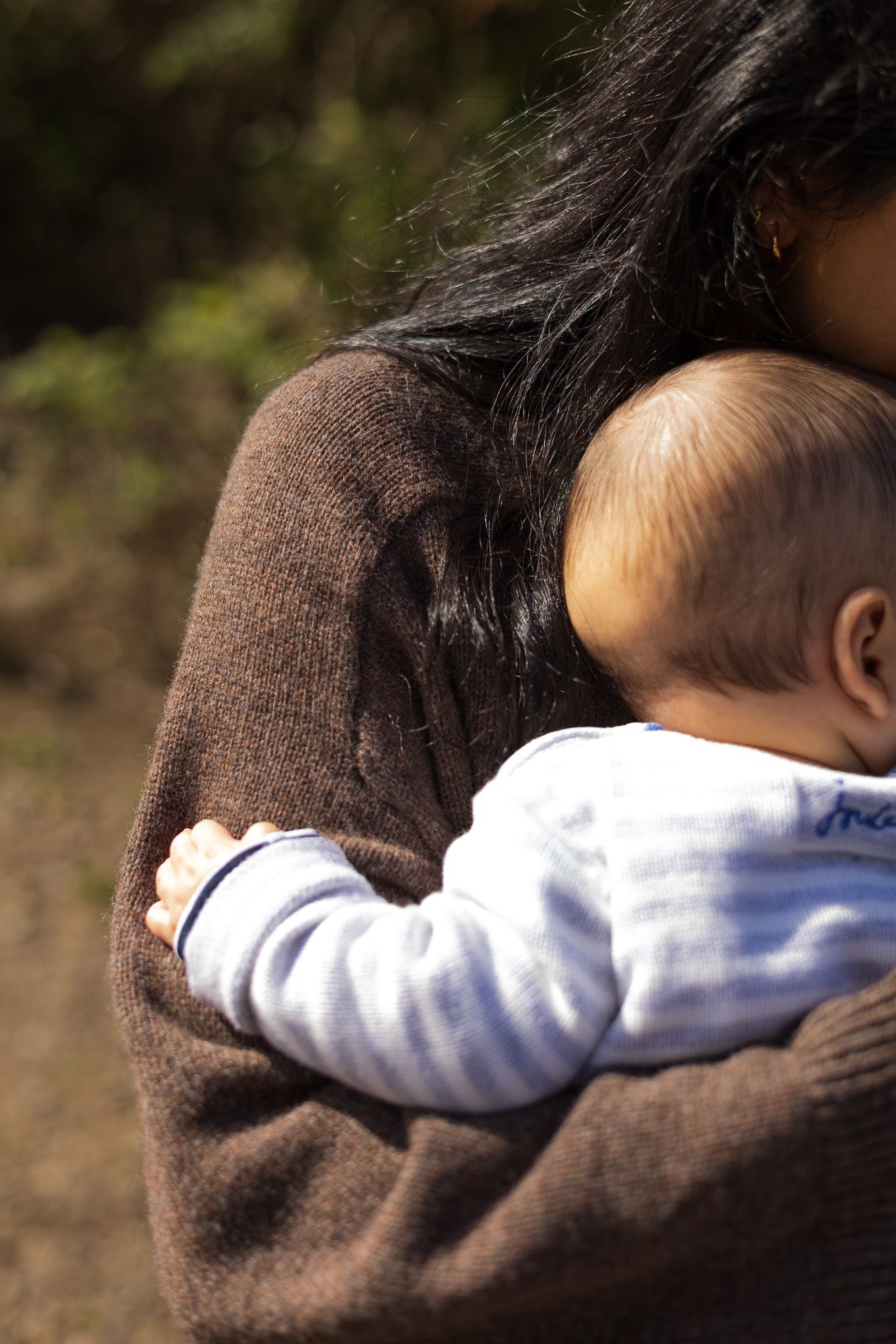 Mother cradling her baby closely in the woods
