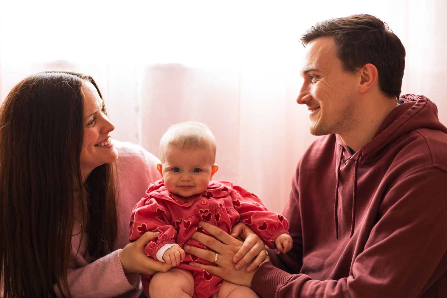 Parents smiling at their baby during a family photoshoot
