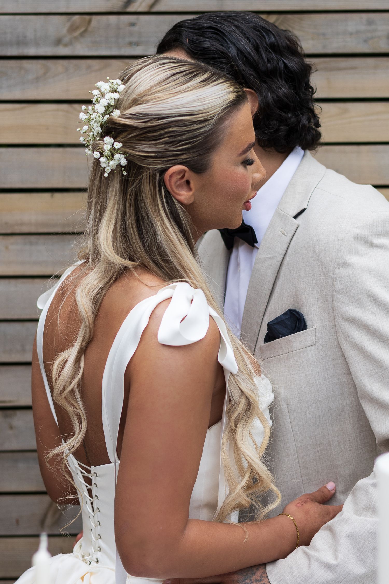 Groom kissing his bride's cheek against a wooden wall backdrop, de courceys manor