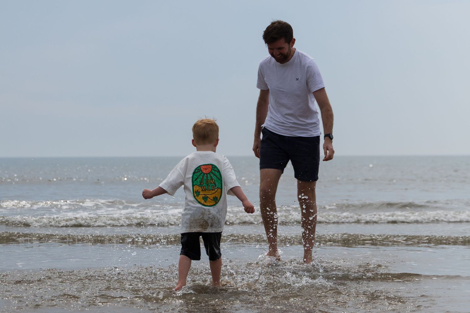 Father and young son paddling together at the beach