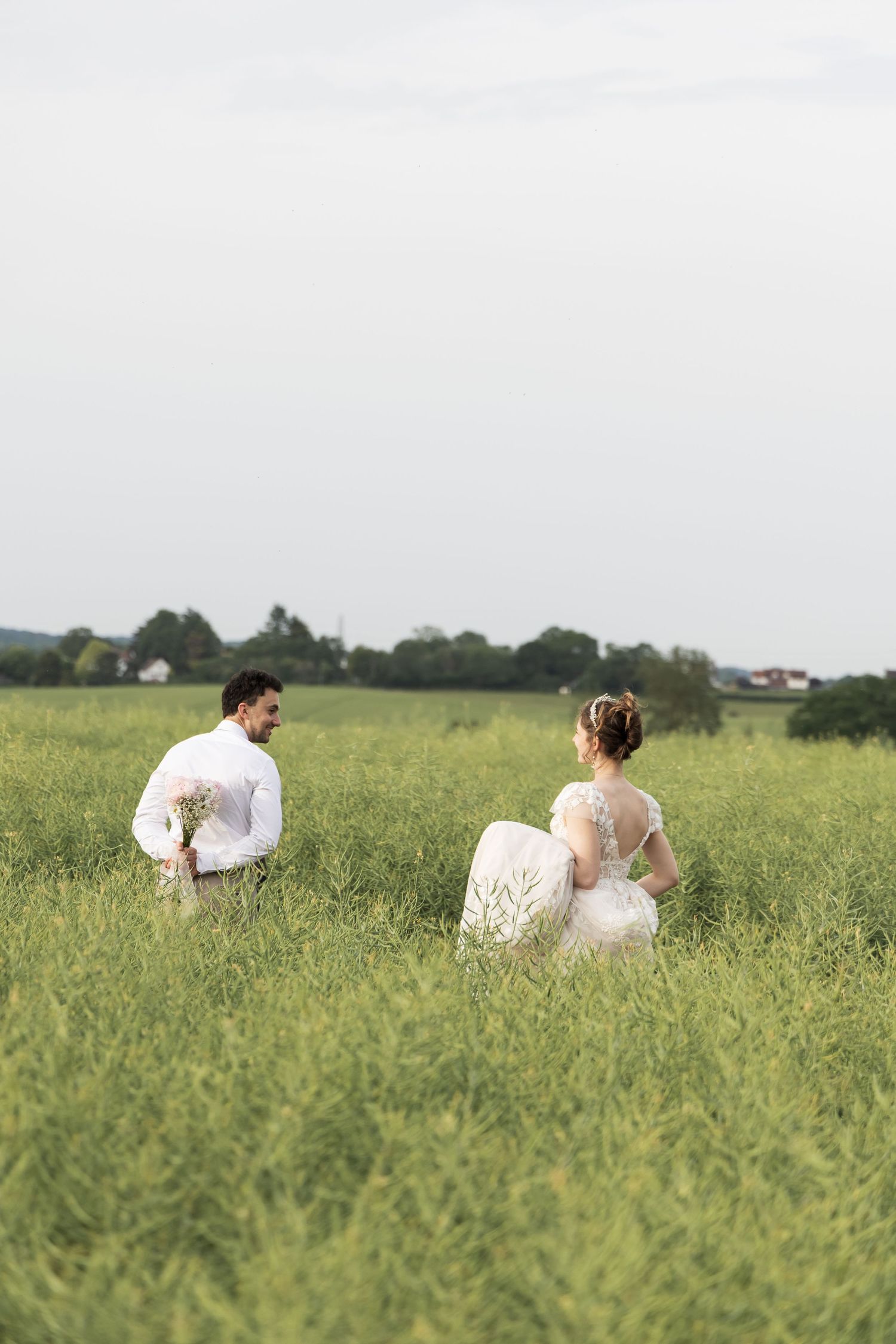Bride and groom sitting together in a grassy field