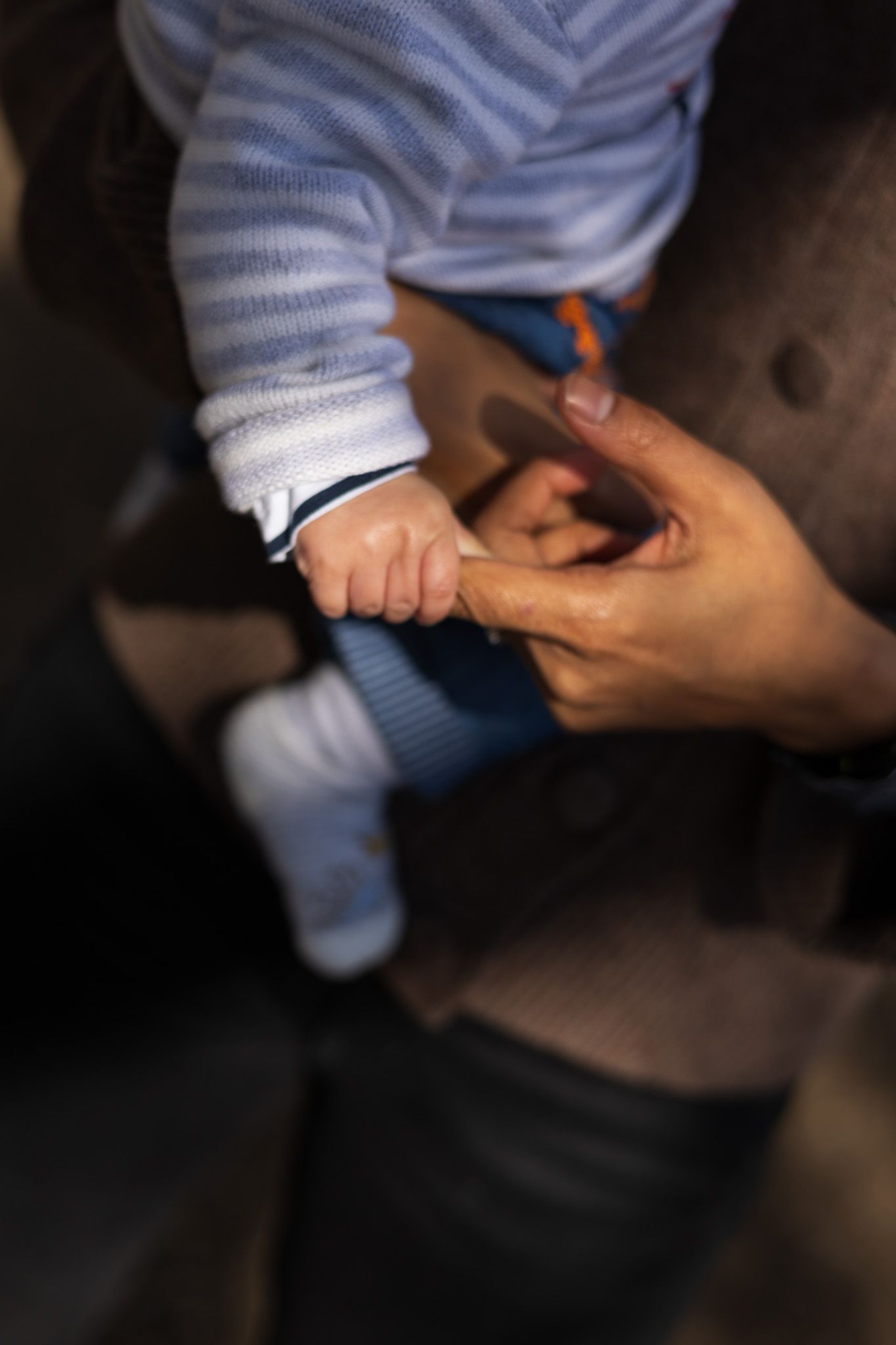 Close-up of a parent's hand gently holding their baby's foot