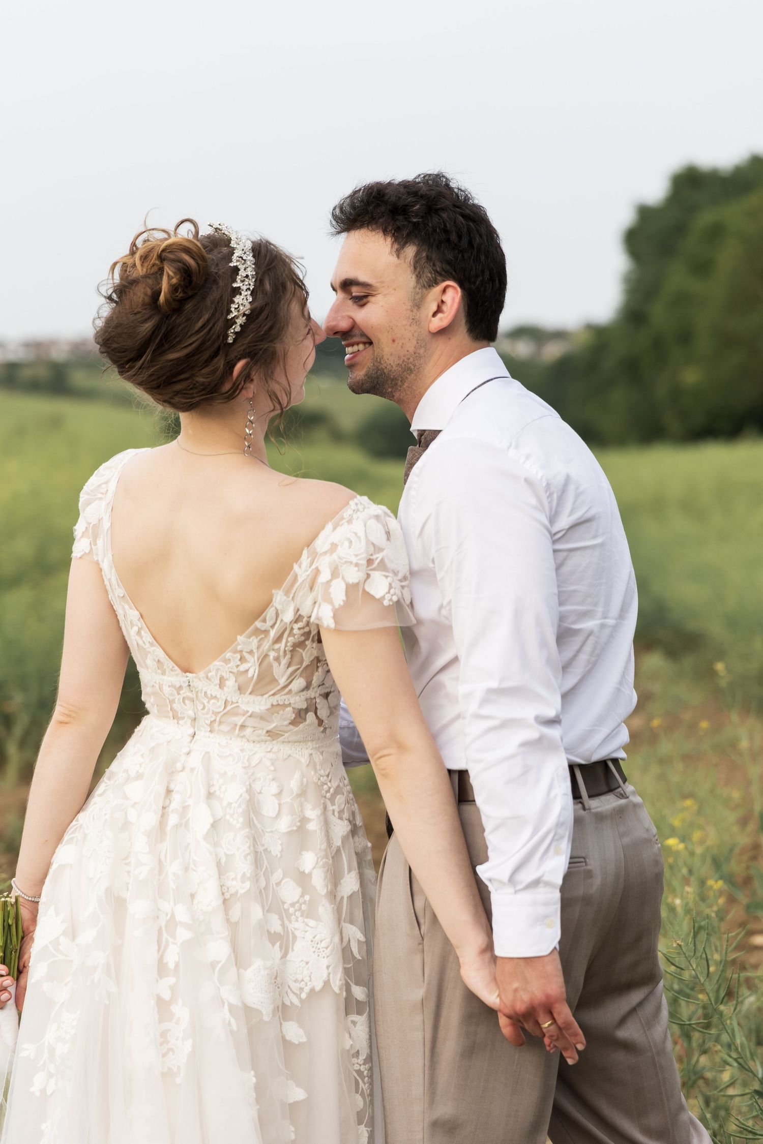 Bride and groom smiling at each other outdoors in a field