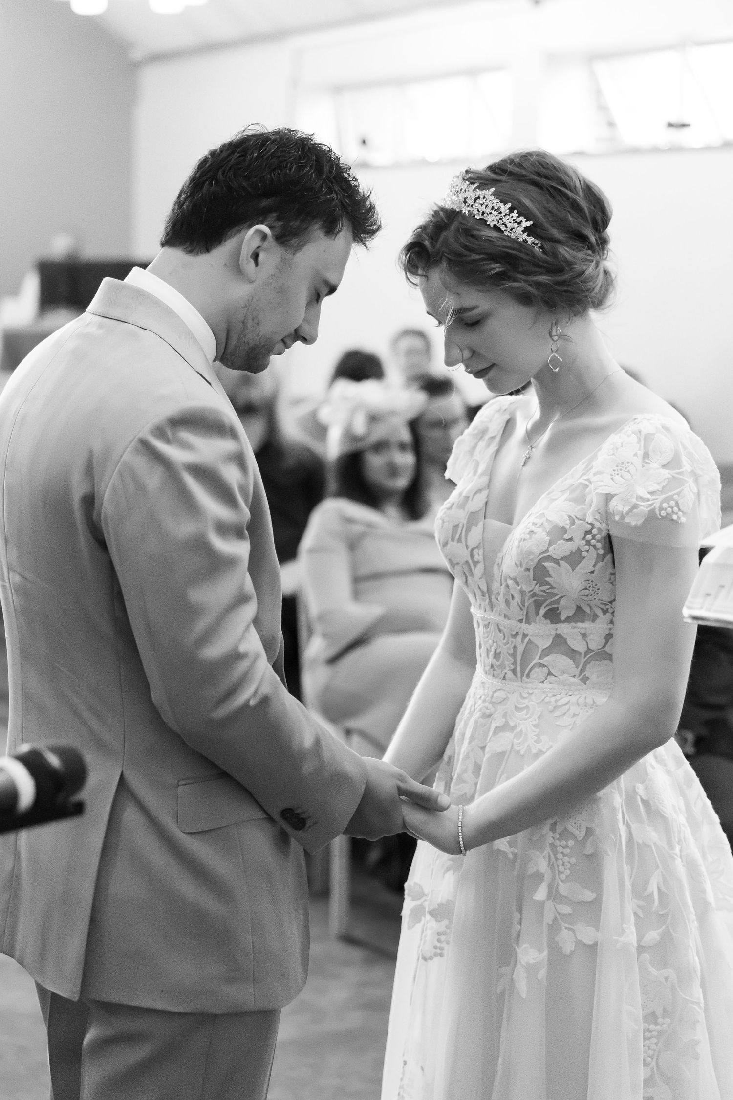 Black and white photo of groom holding bride's hands during the ceremony