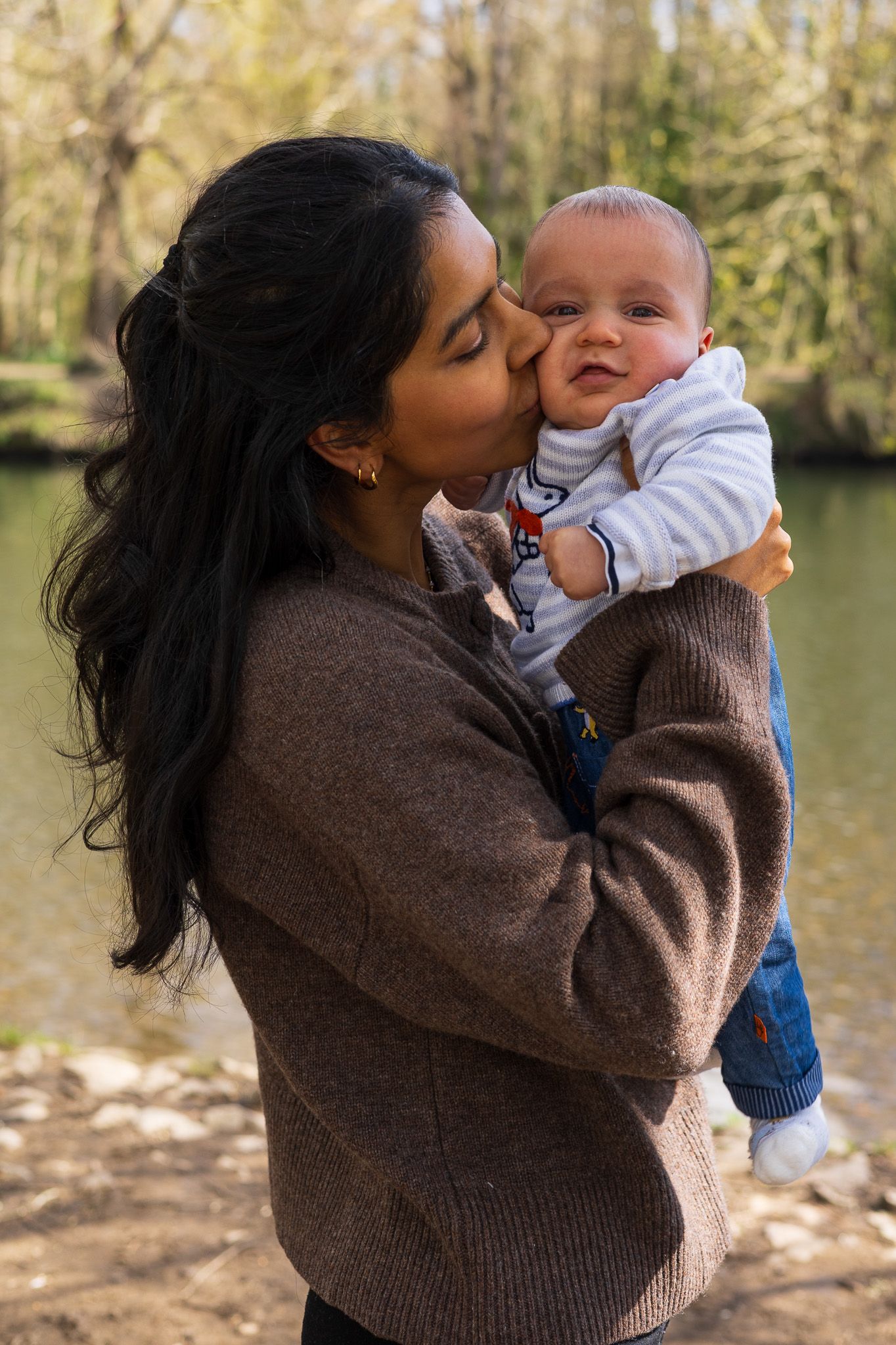 Mother kissing her baby's head during an outdoor family photoshoot