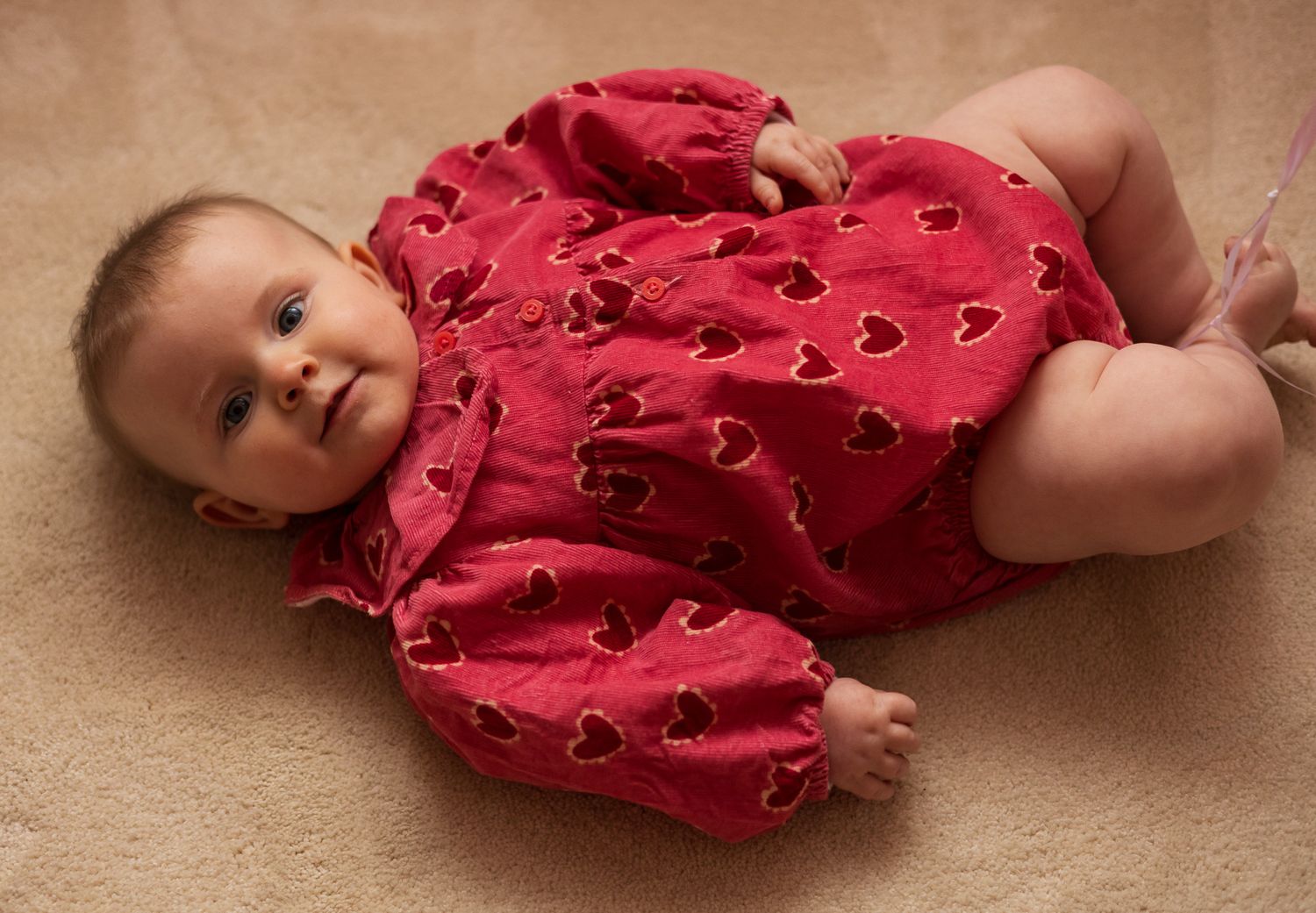 Baby lying on a blanket wearing a red heart-print outfit