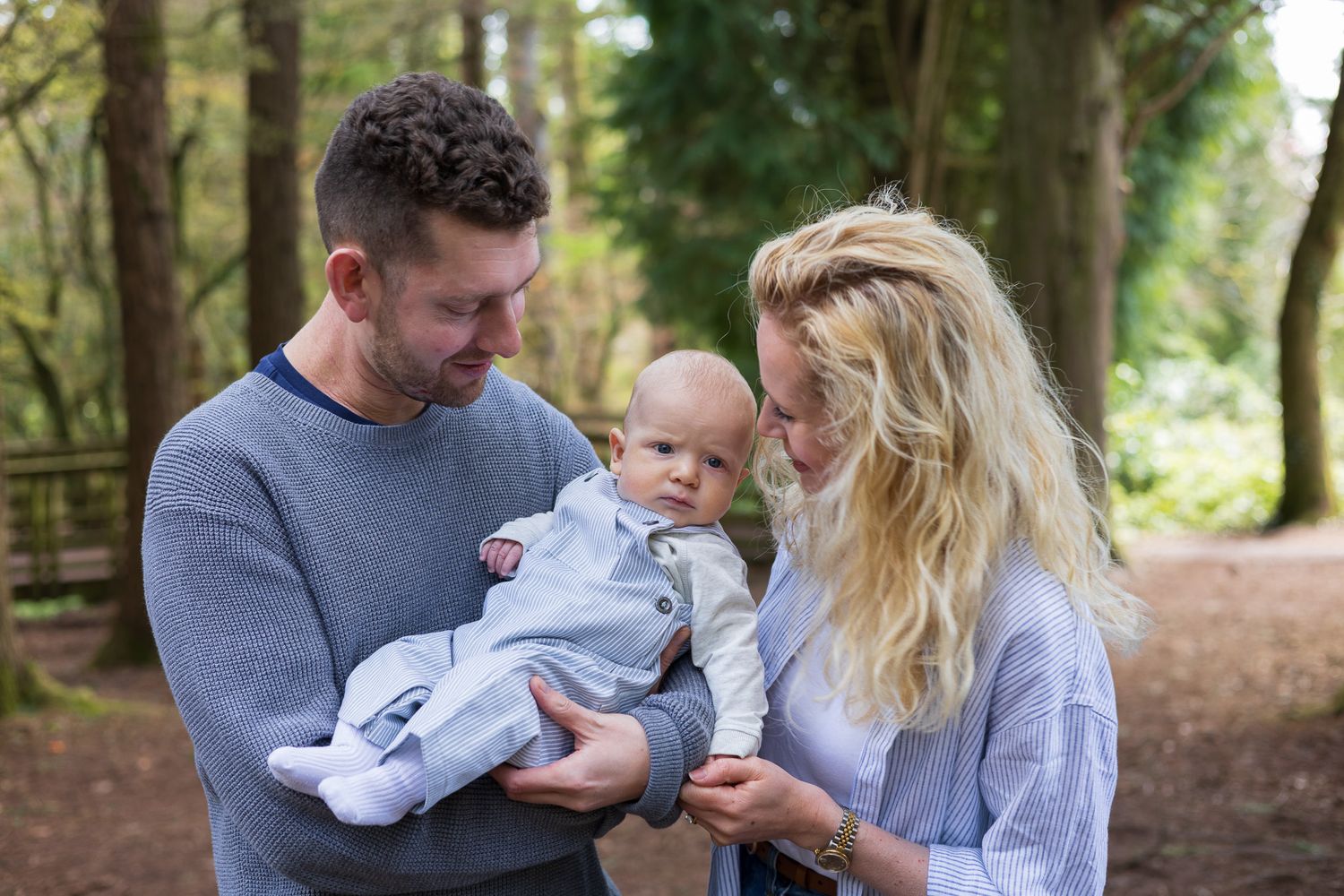Parents smiling down at their baby during a woodland family photoshoot
