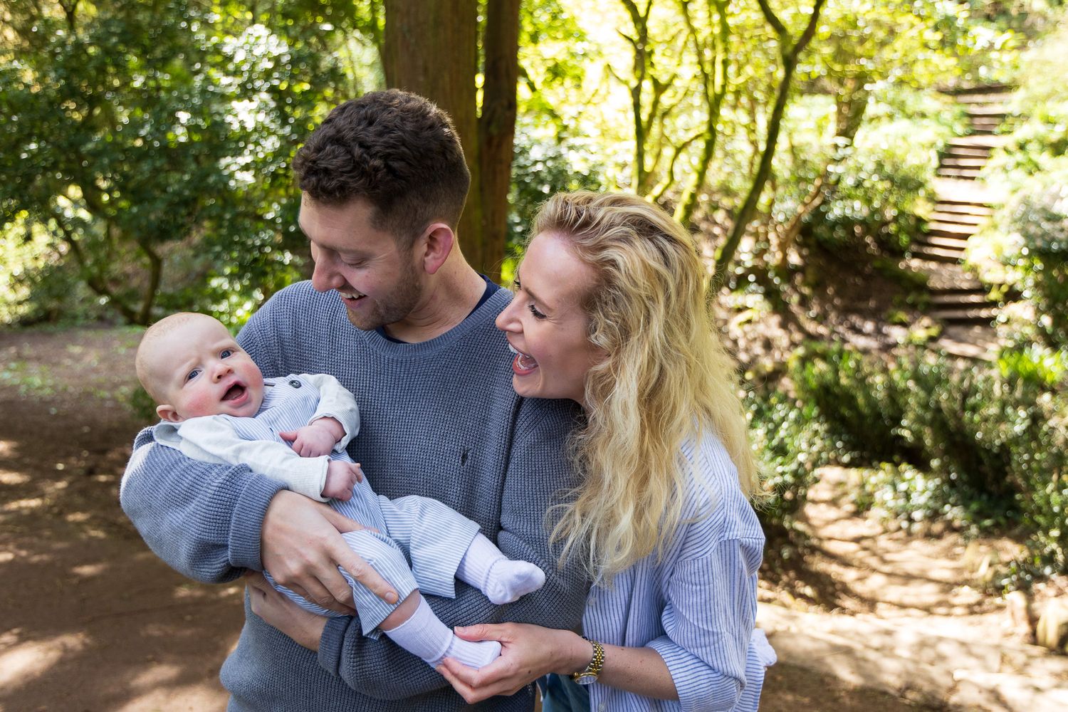Parents walking with their baby along a woodland path