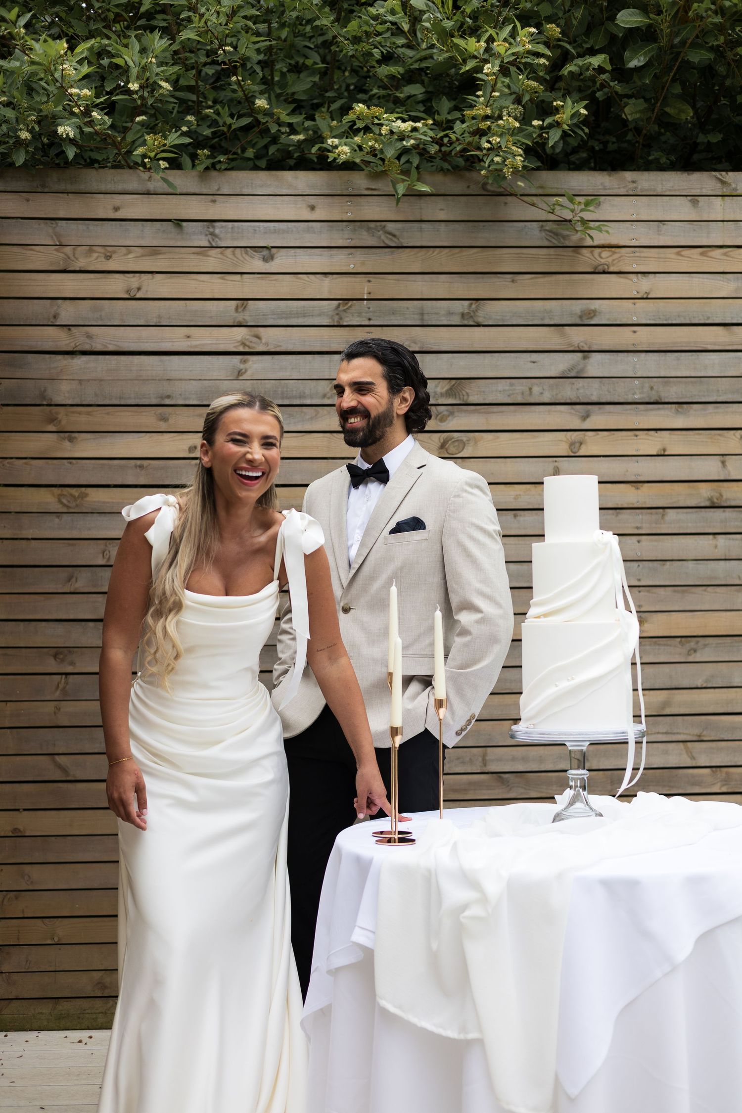 Bride and groom standing beside their wedding cake table, de courceys manor