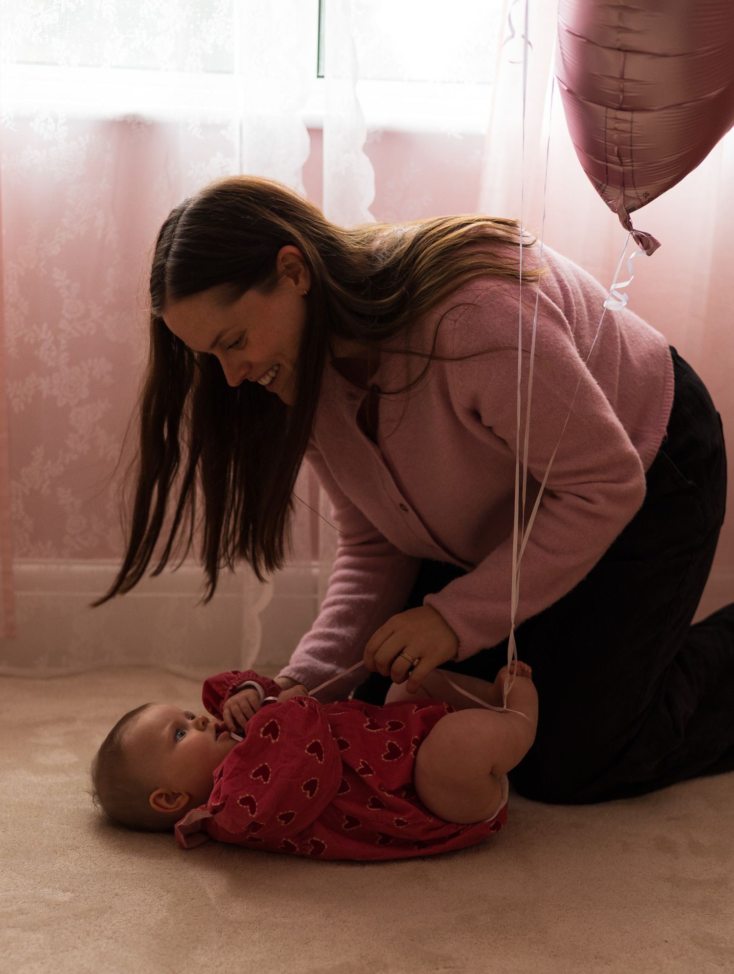 Mother leaning down to play with her baby lying on the floor