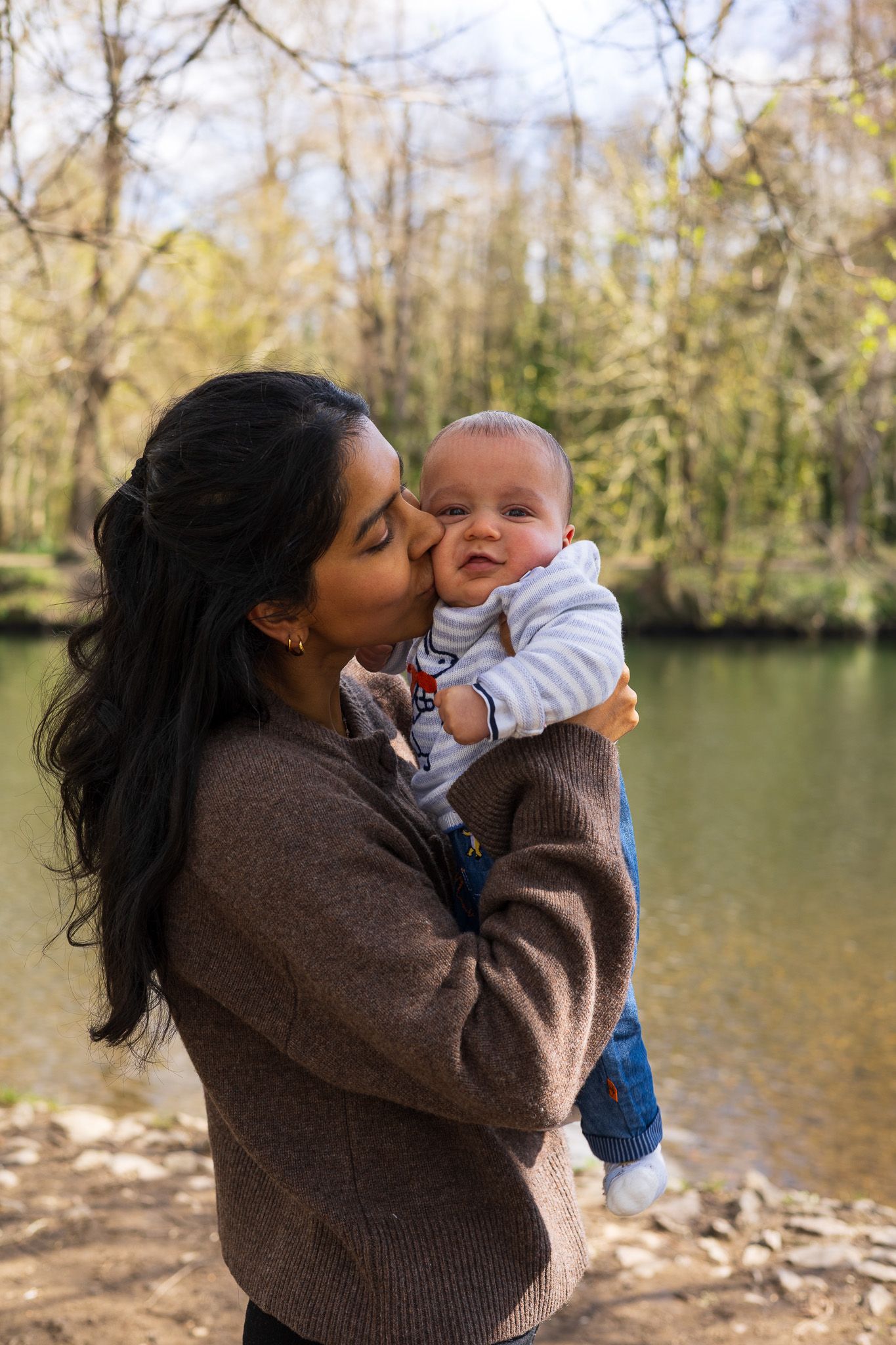 Mother kissing her baby in a woodland setting