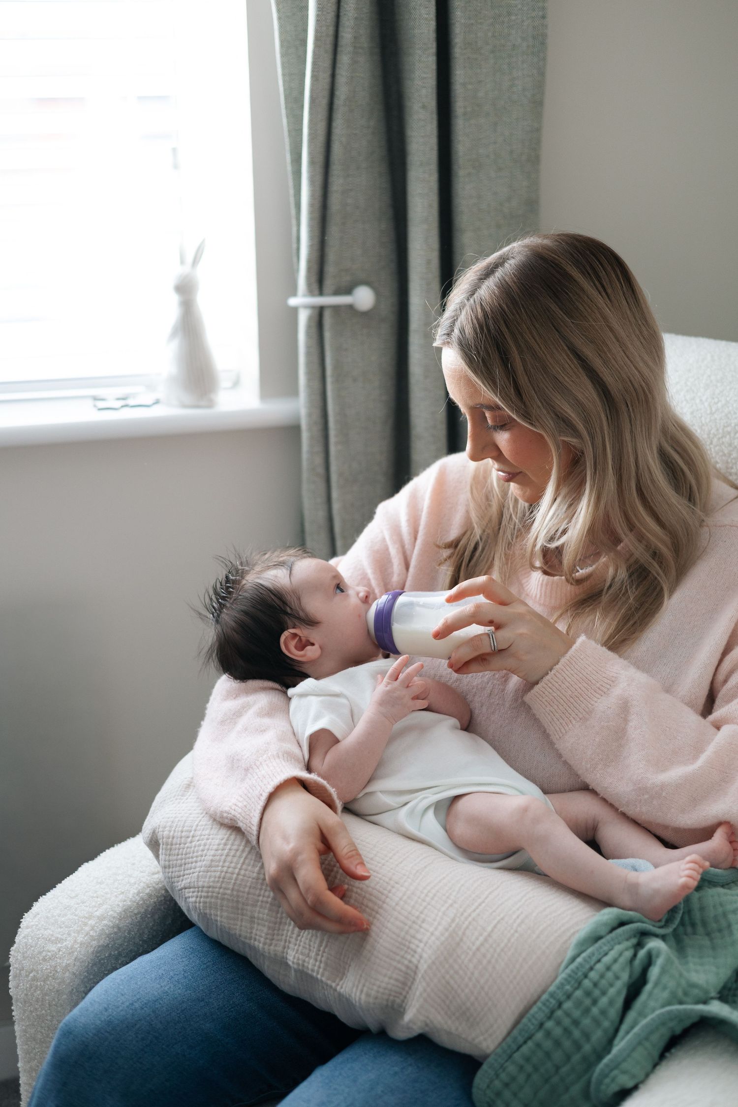 Mother feeding her baby beside a window at home