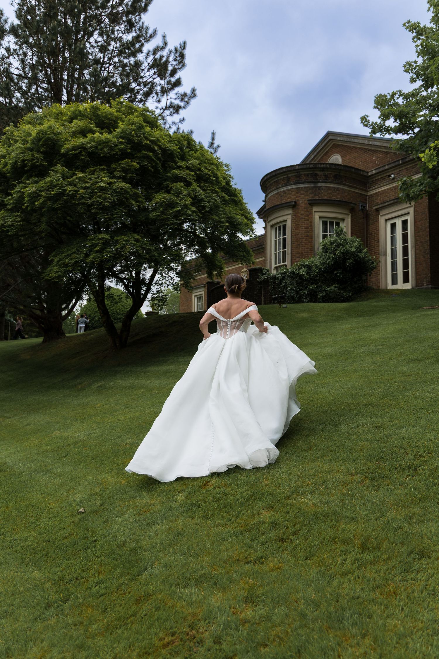 Bride twirling her dress on the lawn in front of a wedding venue, de courceys manor