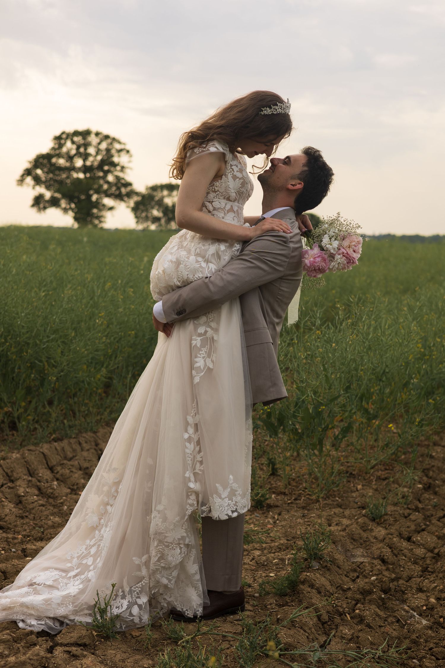 Groom lifting and kissing his bride in a wildflower field